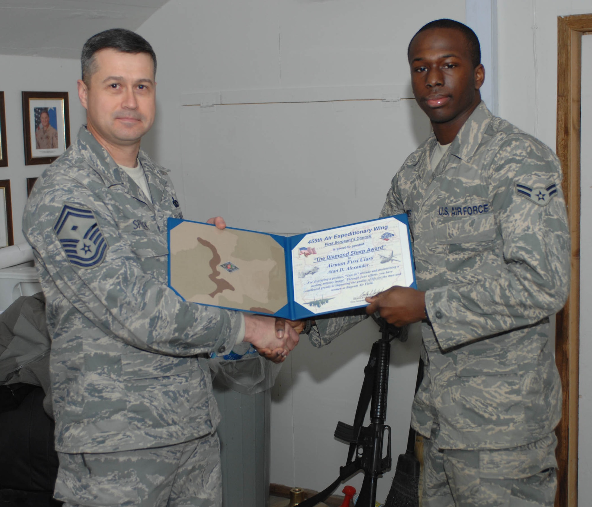 Senior Master Sgt. Bradley Spilinek, 755th Air Expeditionary Group First Sergeant presents a “Diamond Sharp” award to Airman 1st Class Alan D. Alexander, 455th Air Expeditionary Wing Command Post, here Jan. 3.  The Diamond Sharp awards are sponsored by the wing’s first sergeants and recognize individuals that display a positive, “can do” attitude and maintain “a sterling military image at all times.” Sergeant Smith was recognized for his support to Operation Care, a volunteer effort which among several things, provides snacks, hygiene, and morale items to servicemembers at isolated forward operating bases. (U.S. Air Force Photo by Staff Sgt. Mike Andriacco)