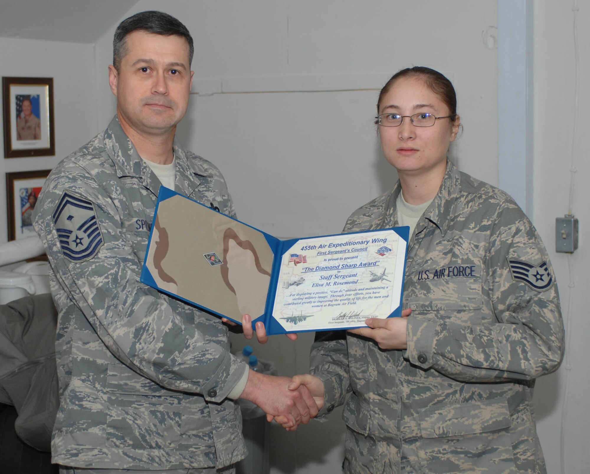 Senior Master Sgt. Bradley Spilinek, 755th Air Expeditionary Group First Sergeant presents a “Diamond Sharp” award to SSgt Elisa M. Rosemond, 455th Expeditionary Logistics Readiness Squadron, here Jan. 3.  The Diamons Sharp awards are sponsored by the wing’s first sergeants and recognize individuals that display a positive, “can do” attitude and maintain “a sterling military image at all times.” Sergeant Smith was recognized for his support to Operation Care, a volunteer effort which among several things, provides snacks, hygiene, and morale items to servicemembers at isolated forward operating bases. (U.S. Air Force Photo by Staff Sgt. Mike Andriacco)
