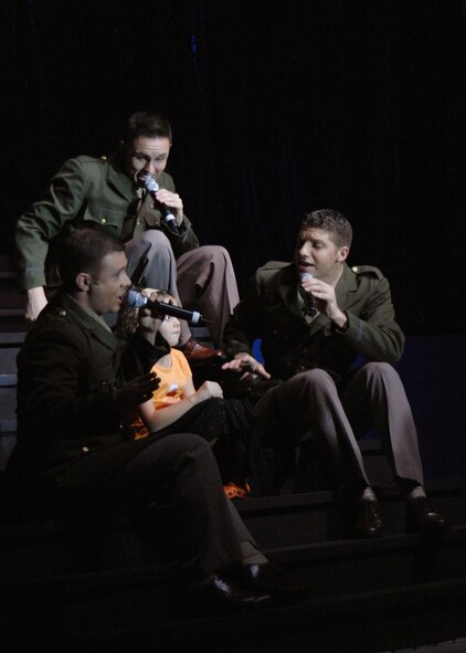 Senior Airmen Nicholas Amari, Benjamin Taylor and Jonathan Hayden perform a musical tribute with the help of a 6-year-old Maggie Menoni, daughter of Commander John Menoni, Helicopter Sea Combat Squadron TWO FIVE Jan. 3. (U.S. Air Force photo/Senior Airman Sonya Padilla)(RELEASED)