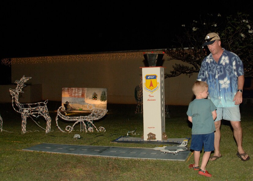 Lt. Col. David Hornyak, 36th Operations Support Group commander, and his son show off the base operations display during Rota Walk Dec. 22, 2007. Rota Walk is an annual event that brings the Andersen community together for the Christmas holiday to view all the commanders' homes that have been decorated by their respective units. (U.S. Air force photo by Airman First Class Zachary Hunter)
