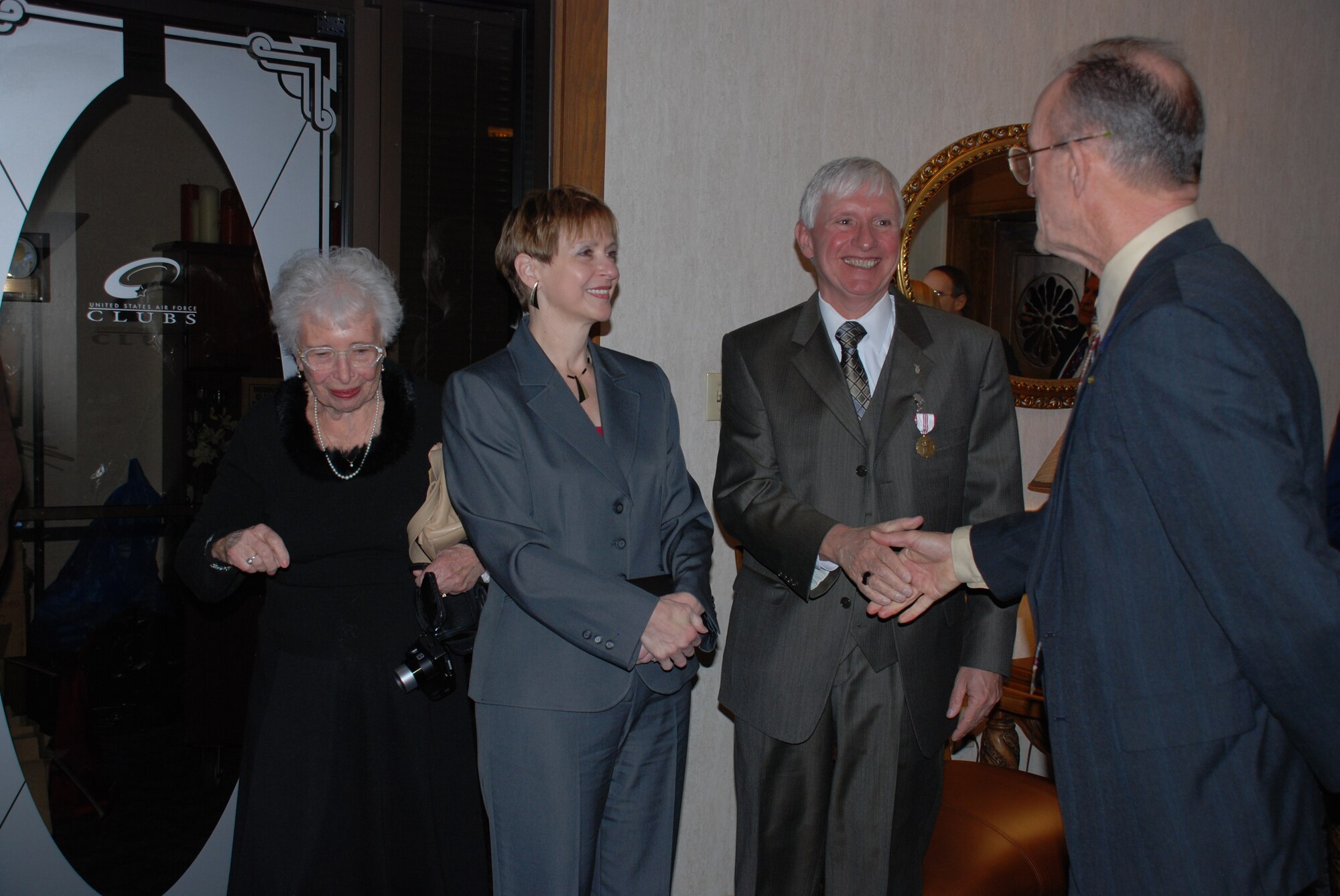Reserve Maj. Gen. (Retired) Ed Mechenbier (right) congratulates Dr. Hendrick W. "Henk" Ruck on his 35 years of service as an Air Force civilian following a ceremony January 4 at the Wright-Patt Club. Looking on fom left are Dr. Ruck's mother, Marjorie Ruck, and his wife, Elaine. (Photo by Chris Gulliford)