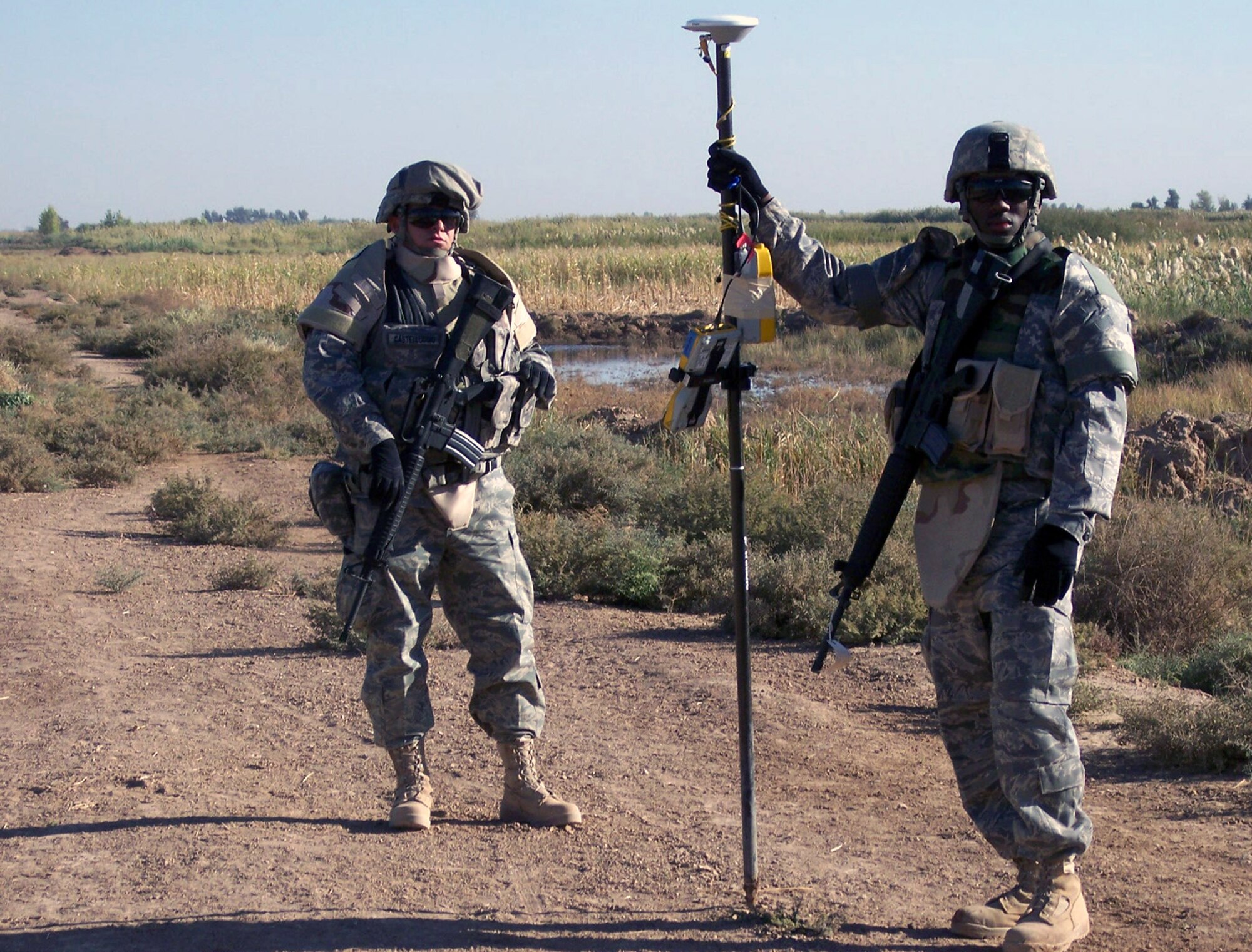 Staff Sgt. Frank Castelluccio (left) provides security as Senior Airman Renardo Sanders mans the surveying equipment at the levee outside Balad Air Base, Iraq, Jan. 7. Both Airmen are 732nd Expeditionary Civil Engineering Squadron engineering assistants. Sergeant Castelluccio is deployed from Kadena Air Base, Japan, and Airman Sanders is deployed from Beale Air Force Base, Calif. (U.S. Air Force photo/Capt. Christopher Mercer) 
