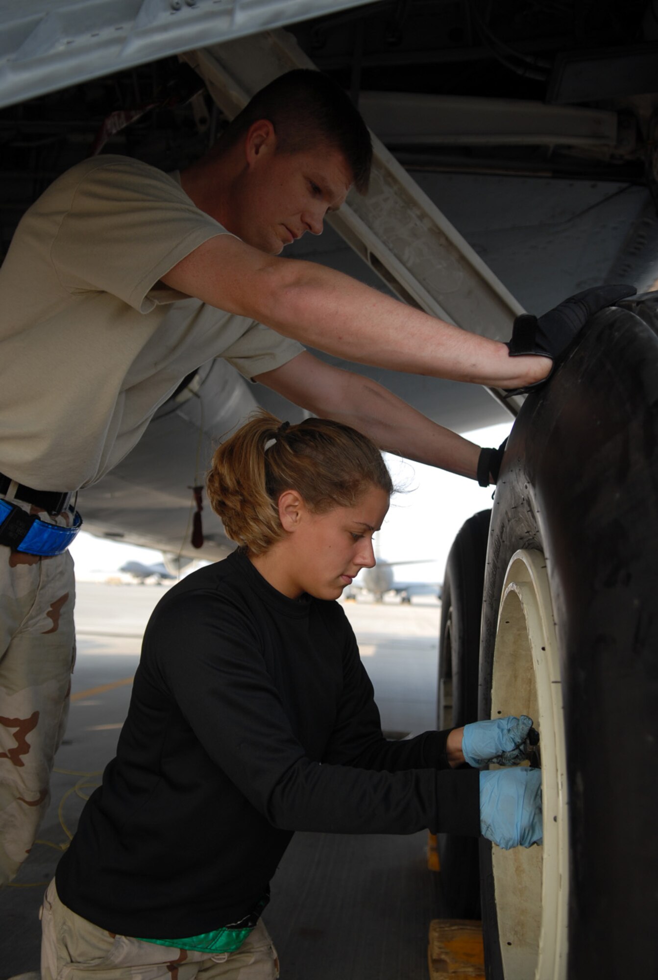 SOUTHWEST ASIA - Staff Sgt. Frank Veres, a crew chief deployed from Fairchild Air Force Base, Wash., holds a new wheel in place while Airman 1st Class Abigail Smith, a crew chief deployed from McConnell Air Force Base, Kan., replaces the lug bolts for a KC-135 Stratotanker at a Southwest Asia air base Jan. 5. (U. S. Air Force photo/Staff Sgt. Douglas Olsen)