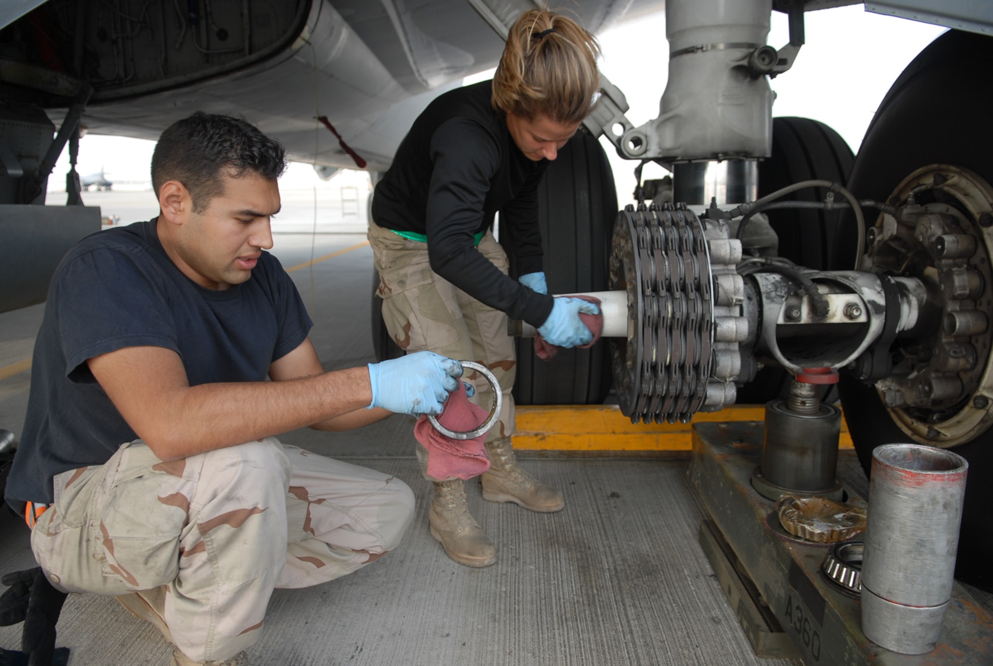 SOUTHWEST ASIA - Staff Sgt. Ruben Mariscal, deployed from MacDill Air Force Base, Fla., prepares a new bearing and Airman 1st Class Abigail Smith, deployed from McConnell Air Force Base, Kan., cleans the axle of a KC-135 Stratotanker at a Southwest Asia air base Jan. 5. The two crew chiefs are with the 379th Expeditionary Aircraft Maintenance Squadron and are preparing to install a new wheel and tire on the aircraft. (U. S. Air Force photo/Staff Sgt. Douglas Olsen)