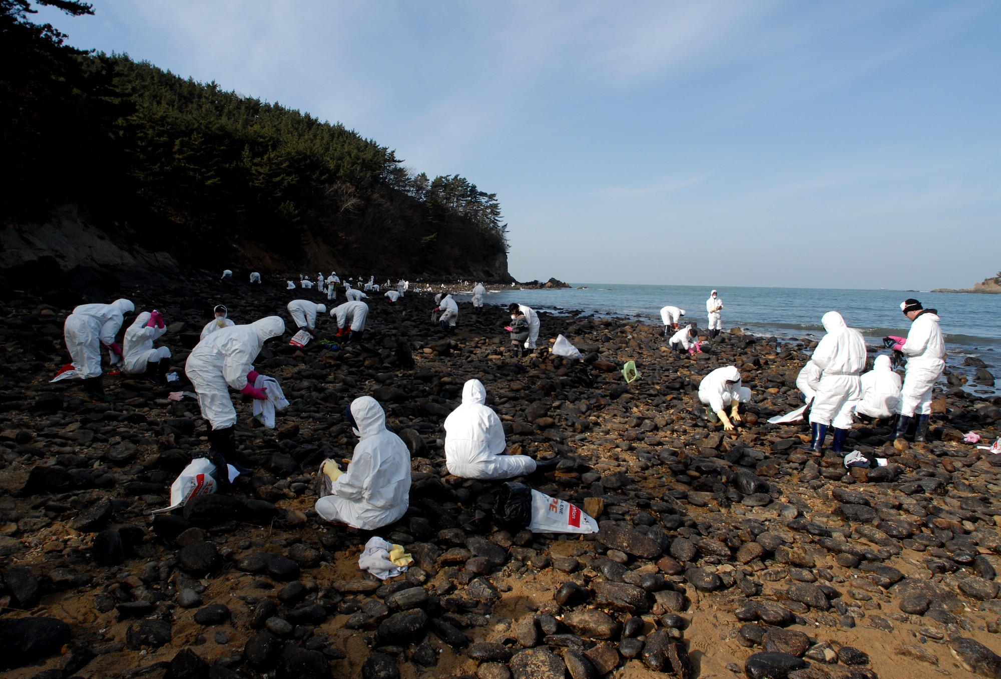 MALLIPO BEACH, South Korea -- Airmen and Soldiers from Kunsan Air Base along with Korean nationals clean rocks after crude oil spilled from a crane barge December 7, 2007 and washed ashore here. Over 200,000 volunteers assisted with the clean up of 2.7 million gallons of oil.  Several agencies, to include 13 helicopters, 17 airplanes, 327 vessels and United States Air Force, Army personnel and Korean nationals took part in the clean up efforts. (U.S. Air Force photo/Senior Airman Steven R. Doty)