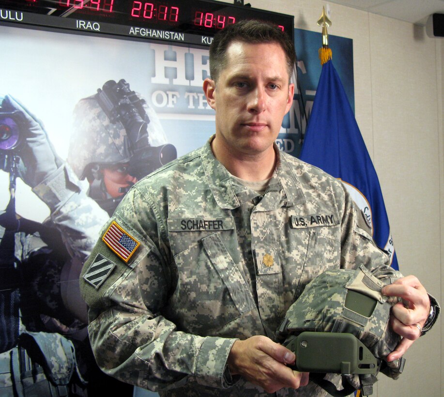 U.S.Army Maj. William Schaffer in the Army’s Program Executive Office Soldier at Fort Belvoir, Va., displays a Kevlar helmet with an externally mounted sensor that collects blast data, and the sensor itself. The 101st Airborne Division is receiving the sensors before deploying to Afghanistan. Photo by Donna Miles

