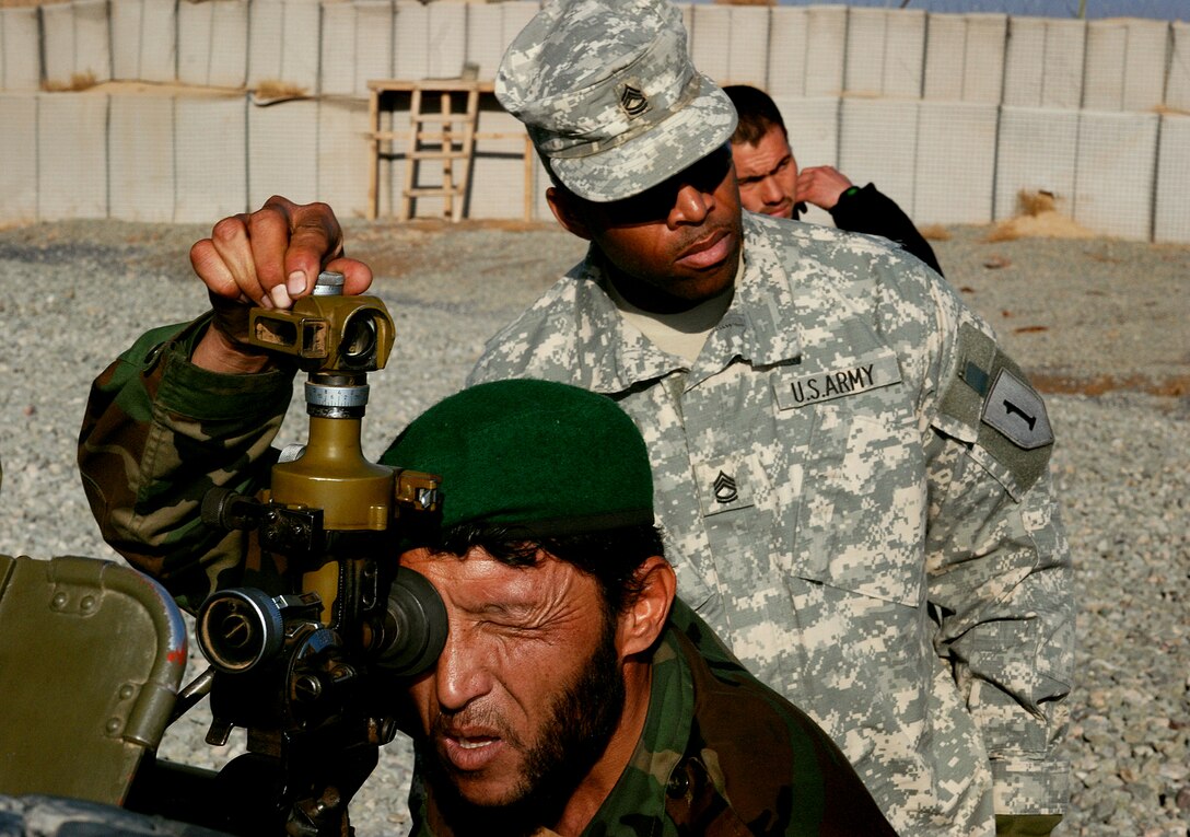 U.S. Army Sgt. 1st Class David Trice of the 4-2 Embedded Training Team  watches as Afghan National Army Platoon Sgt. Paywand Ali y makes adjustments to a D-30 howitzer in Qalat, Afghanistan, Dec. 30, 2007. Trice is a field artillery mentor for the Fourth Kandak of the Afghan army’s 205th Corps.