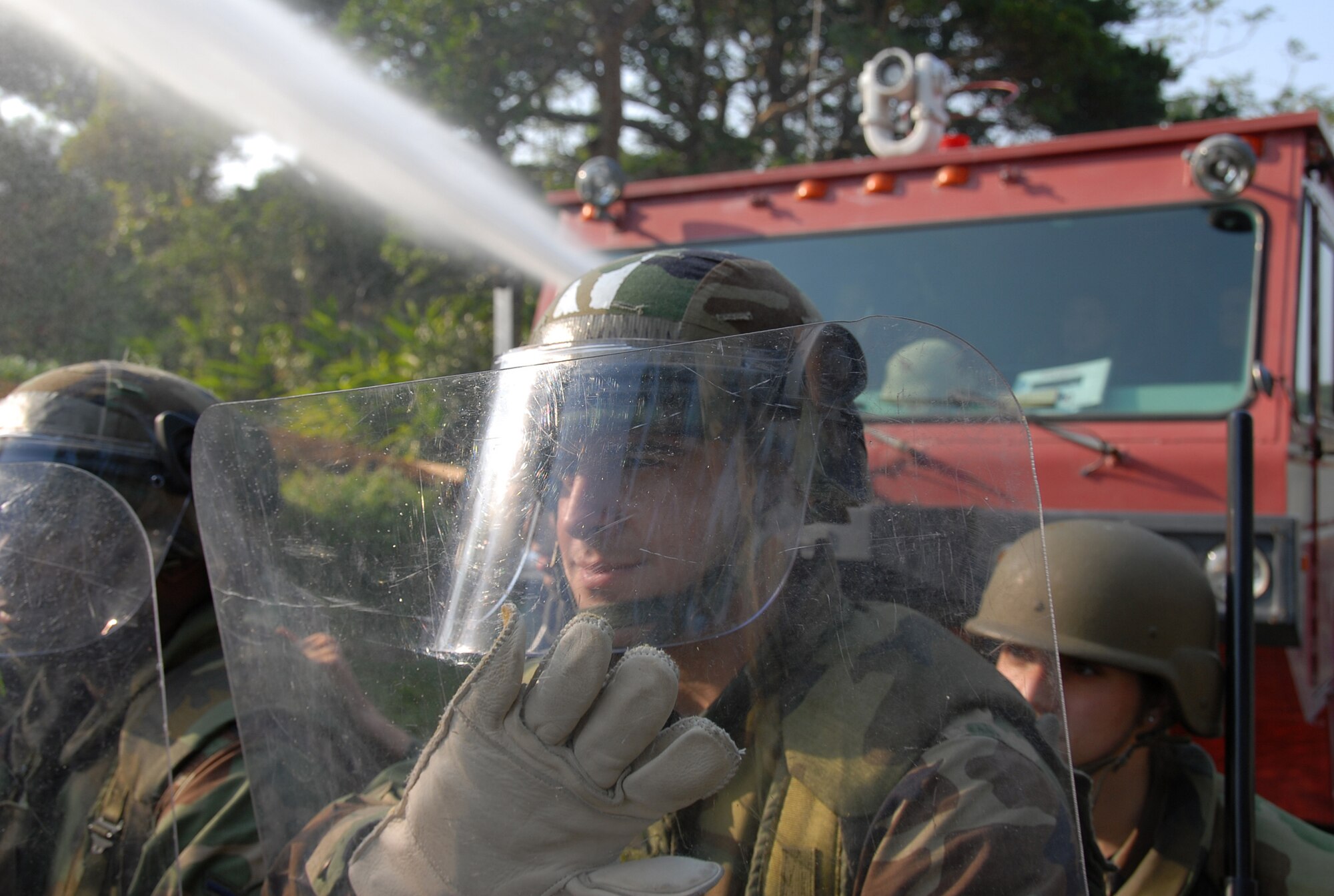 Members of the 18th Security Forces Confrontation Management team respond to a protest as a crash truck sprays water during a simulated protest during Local Operational Readiness Exercise Beverly High 08-3 at Kadena Air Base, Japan, Jan. 7, 2007. The 18th Wing conducted the exercise from Jan. 7 to 11 to test Airmen's ability to respond in contingency situations. (U.S. Air Force photo/Tech. Sgt. Anthony Iusi)