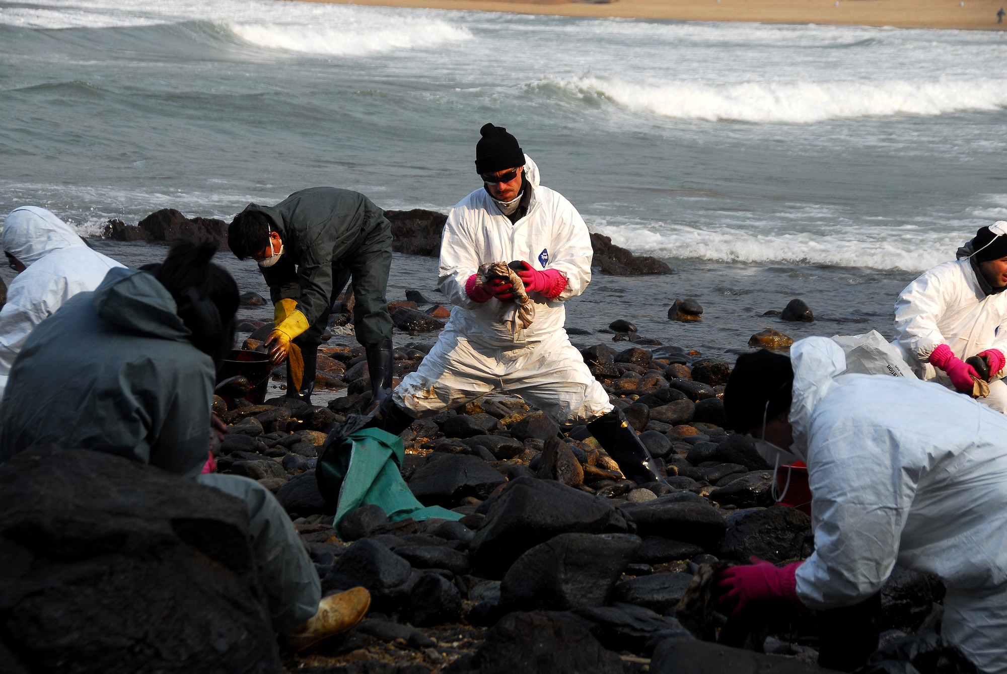 Taean, Republic of Korea -- Tech Sgt. Brian Gregaitis, from Osan Air Base's 51st Civil Engineering Squadron, cleans oil-stained rocks Thursday on the beach near Taean City after the worst crude oil spill in Korean history.  Tech Sgt. Gregaitis is one of 90 volunteers from Osan Air Base.  (U.S. Air Force Photo by Senior Airman Chad Strohmeyer) 
