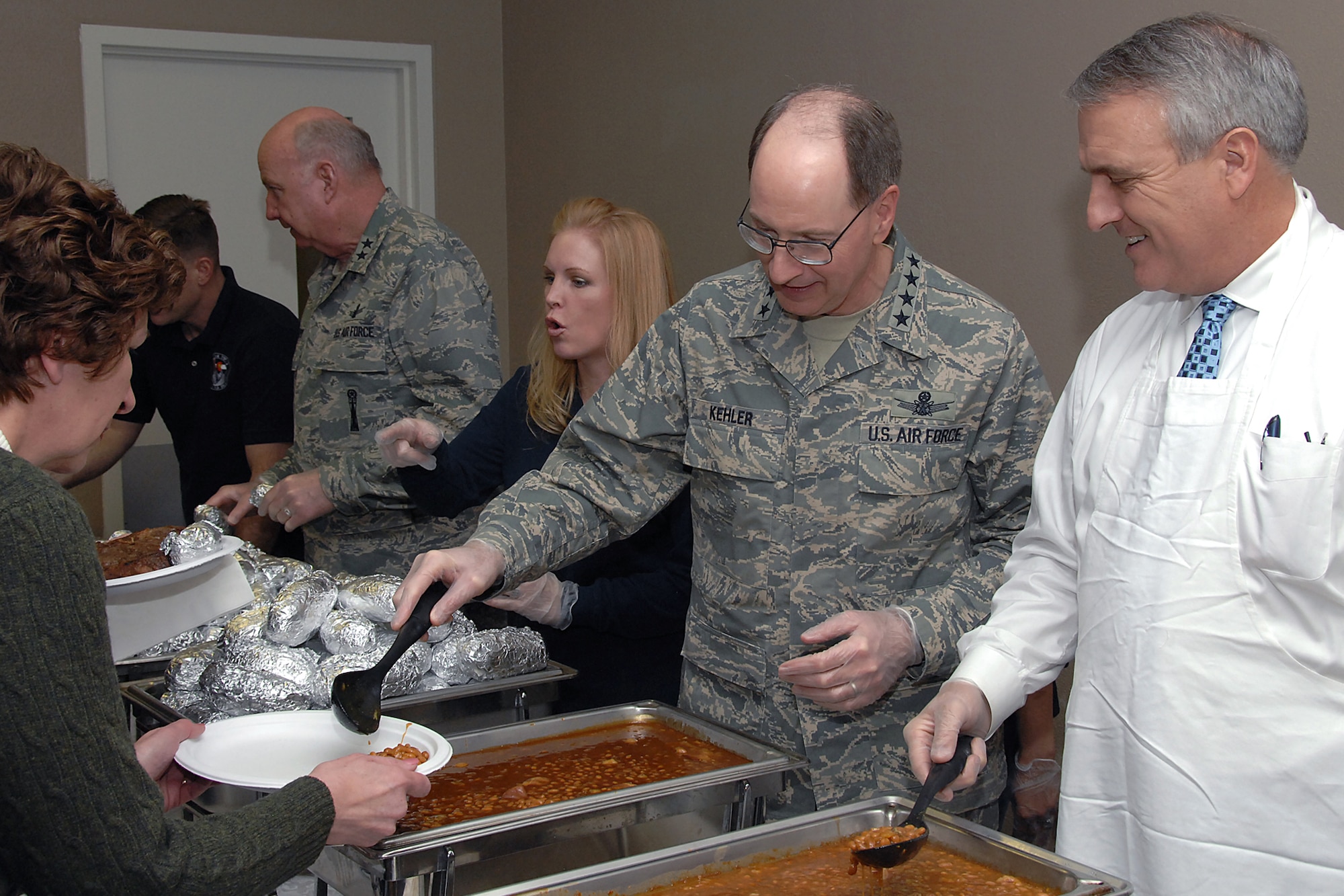 Gen. C. Robert Kehler, commander of Air Force Space Command (left), serves a helping of baked beans to families of deployed Airmen Jan. 4. Colorado Gov. Bill Ritter, Jr. (right) also helped serve dinner. The governor met with the more than 200 family members who attended, expressing his support for them and their deployed spouses. (U.S. Air Force photo/Duncan Wood)