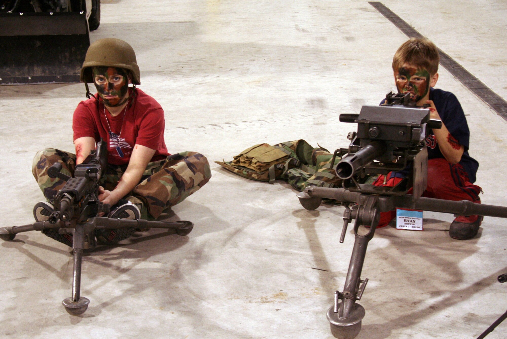 EIELSON AIR FORCE BASE, Alaska-- Christopher and Ryan, sons of Tammy and Lt. Col. Steve Brewer, 353rd Combat Training Squadron, pose at a static gun display after getting their faces painted camouflage Jan. 3 during Operation Bug Out. Operation Bug Out's purpose is to help ease the stress and anxiety that youth may feel due to deployments and local military exercises. The operation is geared towards dependents aged 9-18; the program is a child friendly version of what their parents would experience during a deployment or exercise. For more information, visit www.operationmilitarykids.org. (Airman 1st Class Kurtis Stadsvold)