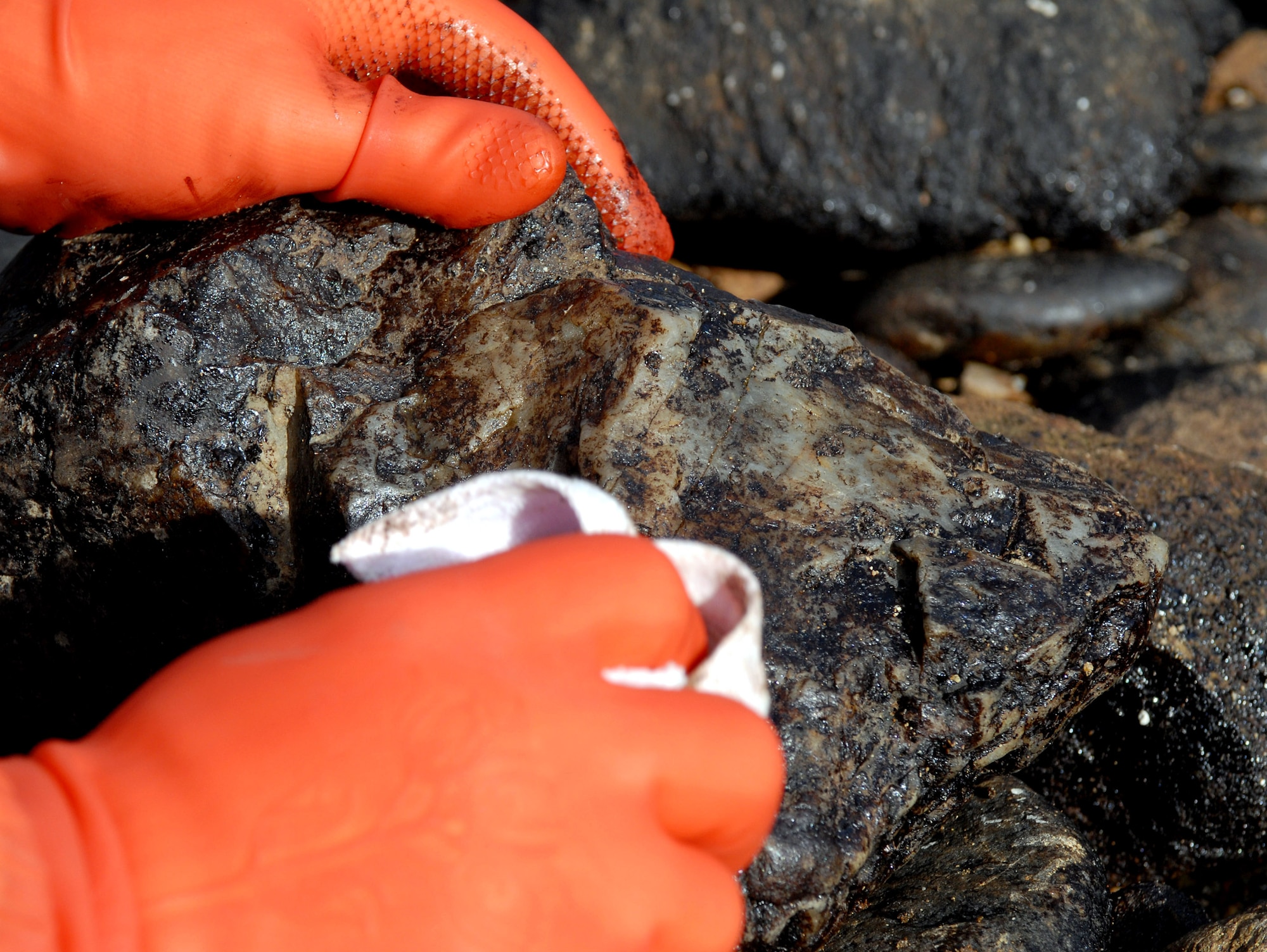 An Airman from Kunsan Air Base cleans a rock after a crude oil spill from a crane barge washed on shore Dec.7 in South Korea. Over 200,000 volunteers assisted with the clean up of 2.7 million gallons of oil. (U.S. Air Force photo/Senior Airman Steven R. Doty)