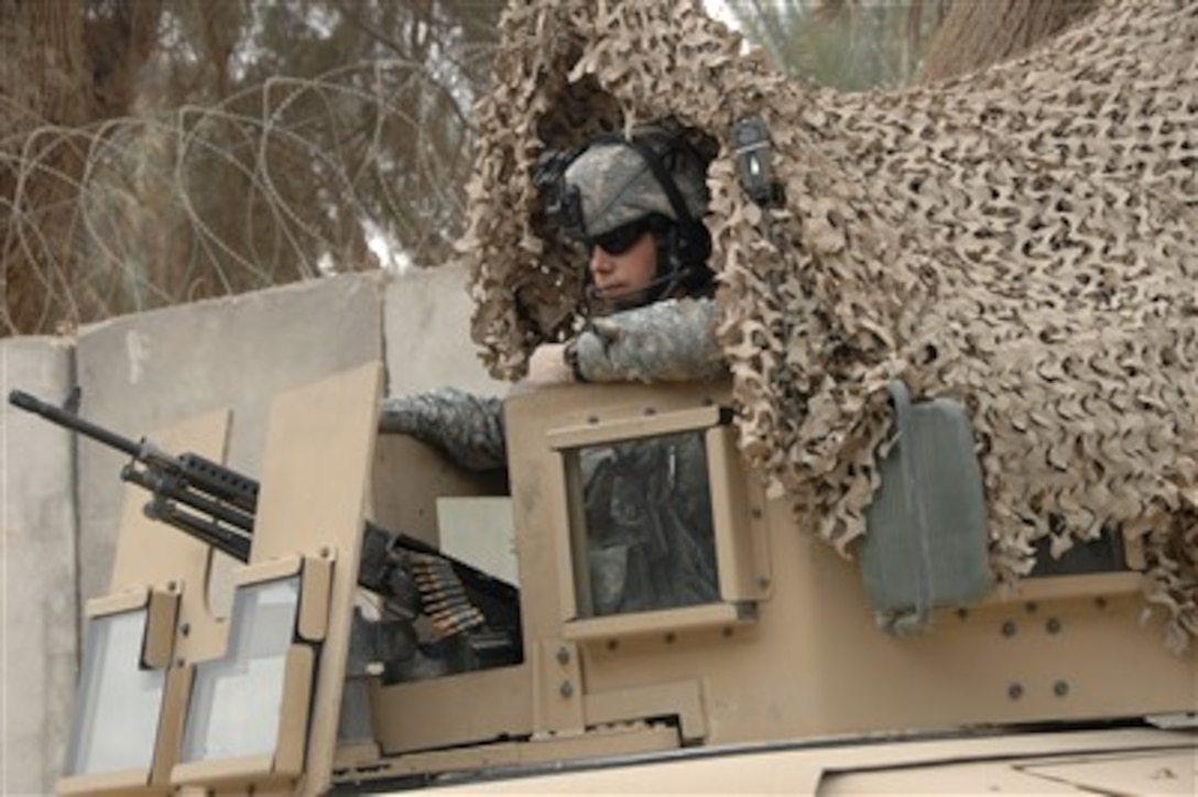 U.S. Army Sgt. Joshua Pagnac peers out from under a camouflage net as he maintains security at an Iraqi police station in Seddah, Iraq, on Jan. 1, 2008.  Pagnac is assigned to Charlie Company, 3rd Battalion, 7th Infantry Regiment, 3rd Infantry Division.  