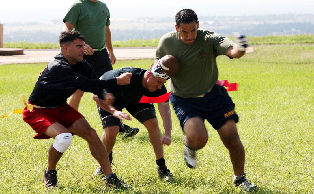 MARINE CORPS BASE, CAMP H.M. SMITH, Hawaii -- SOCPAC wide receivers and utility player, Kennith Sainz, right, blows by two G-6 Marauders players for a 30-yard touchdown run in the semi-final round of the Camp Smith Intramural Flag-Football playoffs.