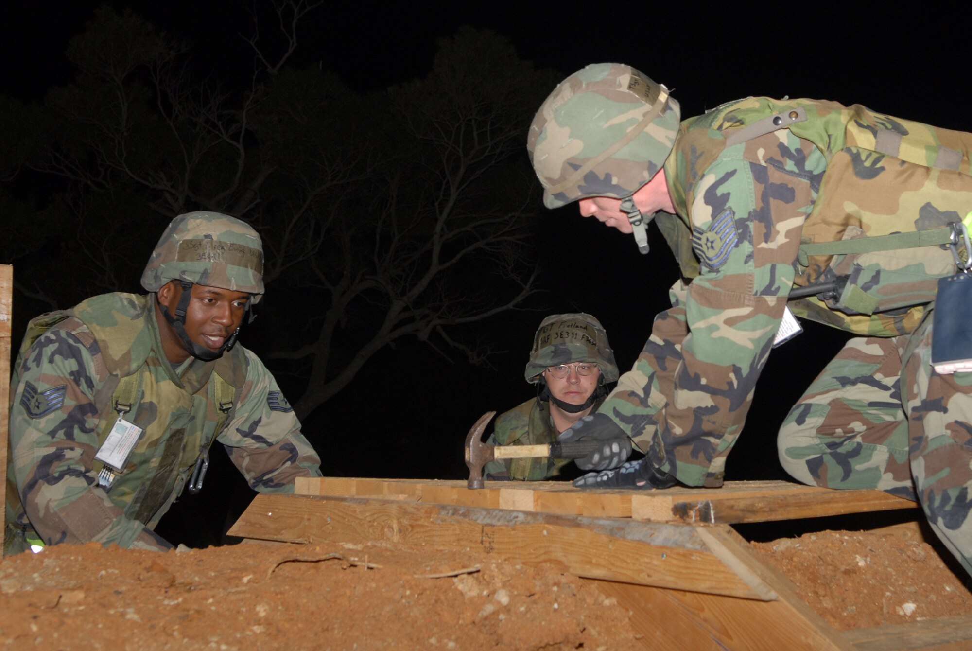 Staff Sgt. Greg Ewing and Staff Sgt. Bryan Froiland, 18th Civil Engineer Squadron, look on as Tech. Sgt. Eric Camp, 18th CES, hammers the last nail in the stairs for a 10,000 gallon fuel berm during a Local Operational Readiness Exercise Beverly High 08-3 scenario at Kadena Air Base, Japan, Jan. 8, 2007. The 18th Wing conducted the exercise from Jan. 7 to 11 to test Airmen's ability to respond in contingency situations. All three Airmen are assigned to the Civil Engineer Squadron (U.S. Air Force photo/Staff Sgt Chrissy FitzGerald)