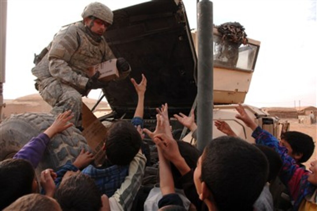 Eager hands reach for a Meals Ready to Eat package being handed out by a U.S. Army soldier attached to the 3rd Squadron, 3rd Armored Cavalry Regiment in Mosul, Iraq, on Jan. 4, 2008.  