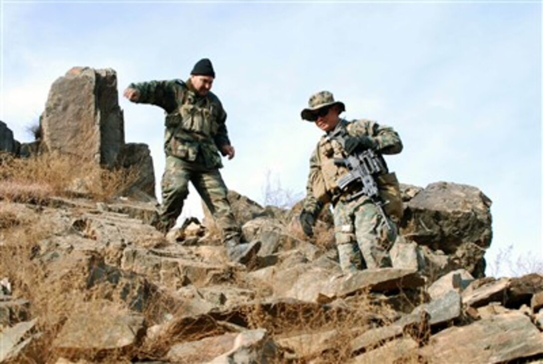 Afghan National Army Maj. Abdul Latif (left) follows U.S. Navy Petty Officer 1st Class Reynaldo S. Datu down a rugged hillside to a border checkpoint 500-meters below the top of a mountain in Afghanistan on Jan. 3, 2008.  Latif is the executive officer of 3rd Kandak (Armored) Battalion, 3rd Brigade Combat Team, 201st ANA Corps.  