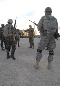 Senior Airman Jeff Ray (center), Survival, Evasion, Resistance and Escape Specialist, speaks to his squad about team movements during the practical application of classroom-taught skills at Common Battlefield Airman Training at Camp Bullis, Texas, Dec. 20. During the training, students were taught how to react to enemy fire and other team movements, such as crossing a danger area. (U.S. Air Force photo by SSgt. Beth Del Vecchio)