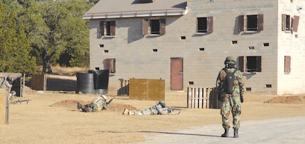 Students of the Common Battlefield Airman Training Bridge course react to enemy fire as part of the final field training exercise, Dec. 20, while cadre looks on. Students use skills taught throughout the week to successfully maneuver into a village. (U.S. Air Force photo by SSgt. Beth Del Vecchio)