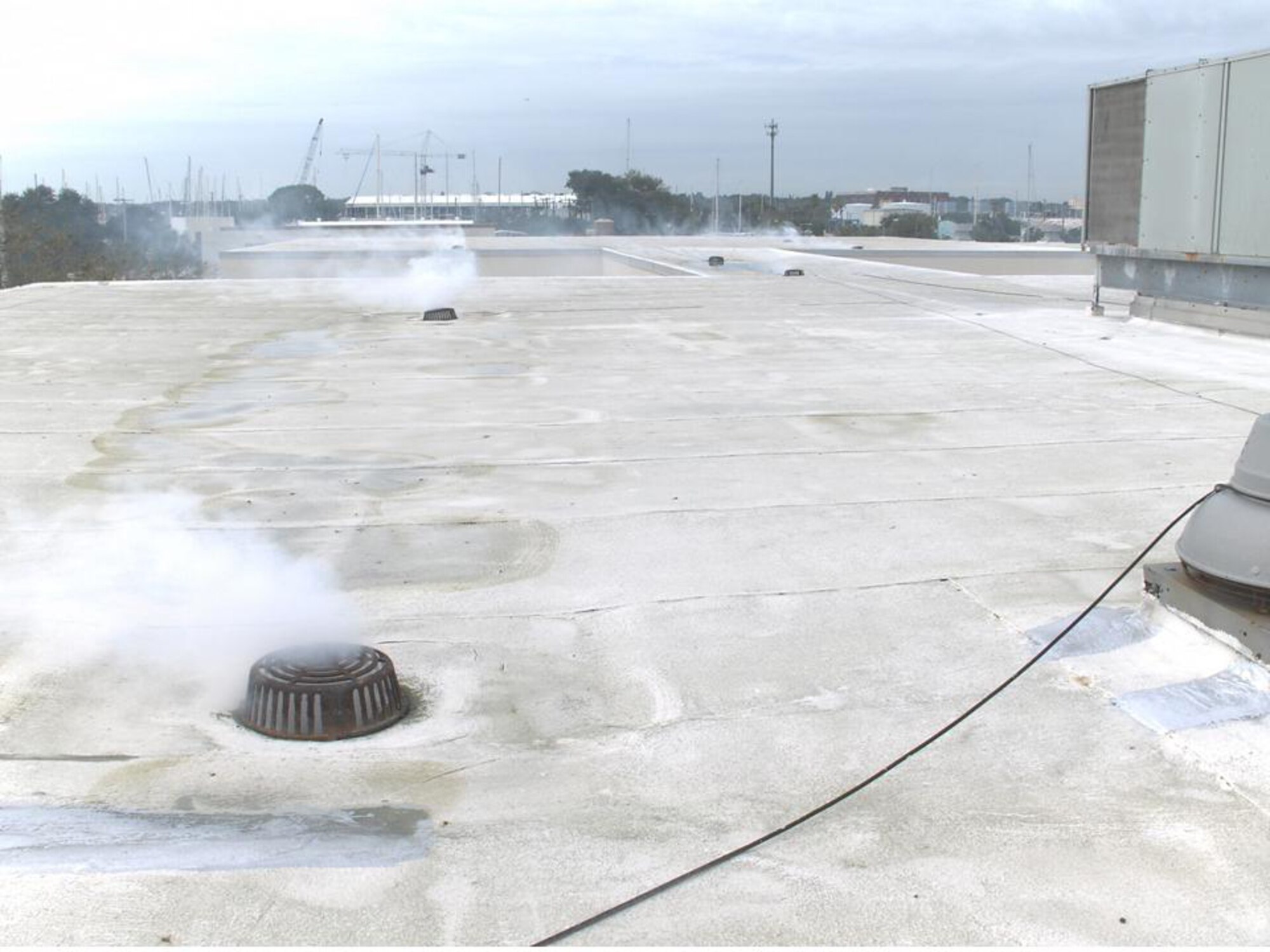 Smoke escapes roof drains during a smoke test conducted at Tyndall Air Force Base.  (Photo Courtesy of the 325th Civil Engineer Squadron)