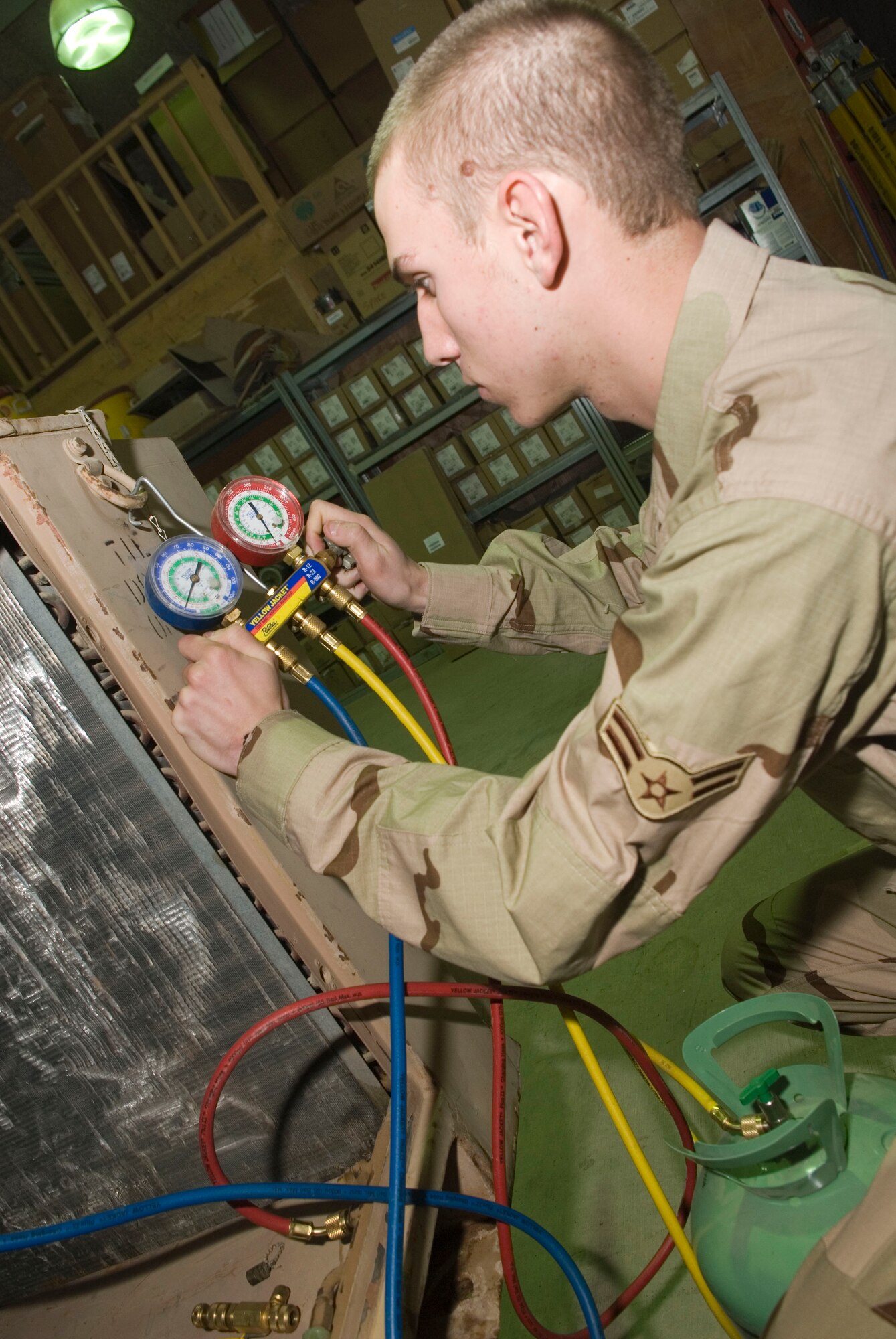 BALAD AIR BASE, Iraq -- Airman 1st Class Brandon Bolden, a 332nd Expeditionary Civil Engineer Squadron heating, ventilation and air conditioning technician, charges an environmental control unit with refrigerant here, Jan. 10. The refrigerant prevents the unit from over heating. Airman Bolden is deployed from Ellsworth Air Force Base, S.D. (U.S. Air Force photo/Staff Sgt. Joshua Garcia)
