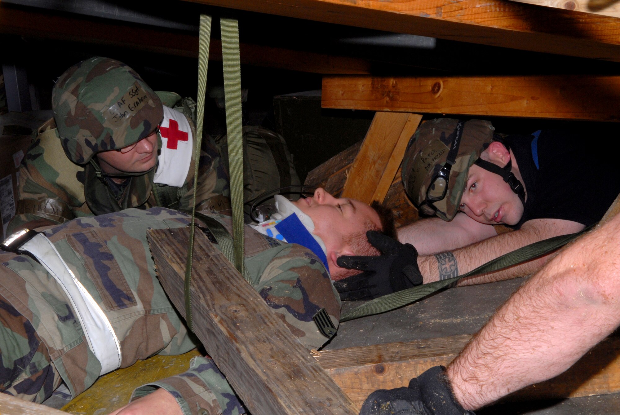 Master Sgt. Stephen Patch, 18th Civil Engineer Group, holds the head of Senior Airman James Wells, 718th Aircraft Maintenance Squadron, in place while Staff Sgt. John Graham, 18th Aerospace Medical Squadron checks SrA Wells medical condition, as he is trapped under debris from a structural and fire scenario in Bldg. 798, during Local Operational Readiness Exercise Beverly High 08-3 at Kadena Air Base, Japan, Jan. 9, 2007. The 18th Wing conducted the exercise from Jan. 7 to 11 to test the wing's ability to respond in contingency situations. (U.S. Air Force photo/Staff Sgt. Chrissy FitzGerald)