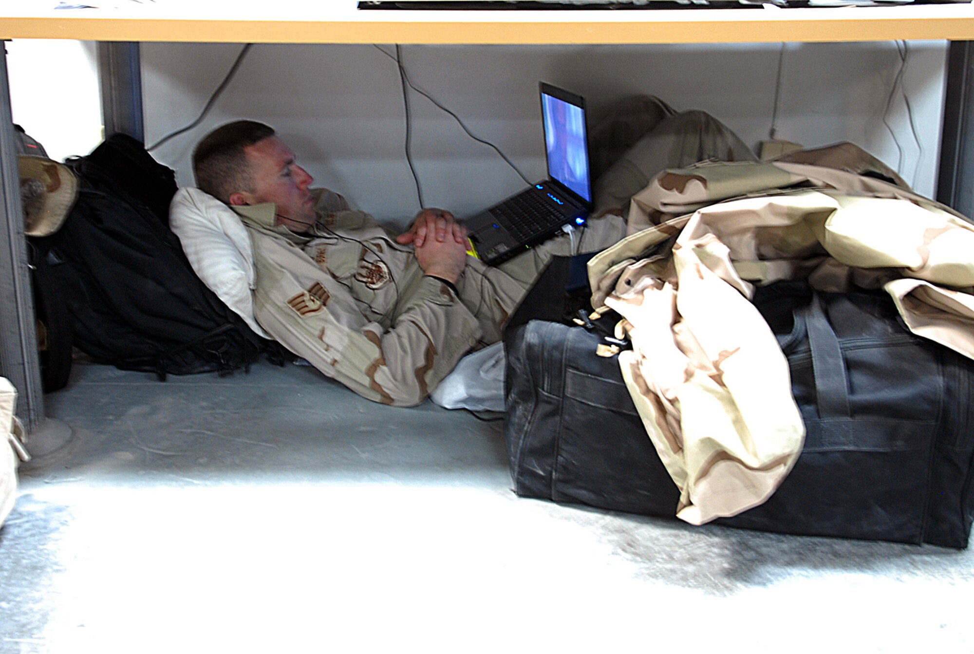 SOUTHWEST ASIA - A homeward bound airman finds a quiet spot to view a movie on his laptop at a Southwest Asia air base passenger terminal Jan. 7.  The terminal is packed with military and civilians waiting to rotate back to their home stations. (U. S. Air Force photo/Staff Sgt. Douglas Olsen)