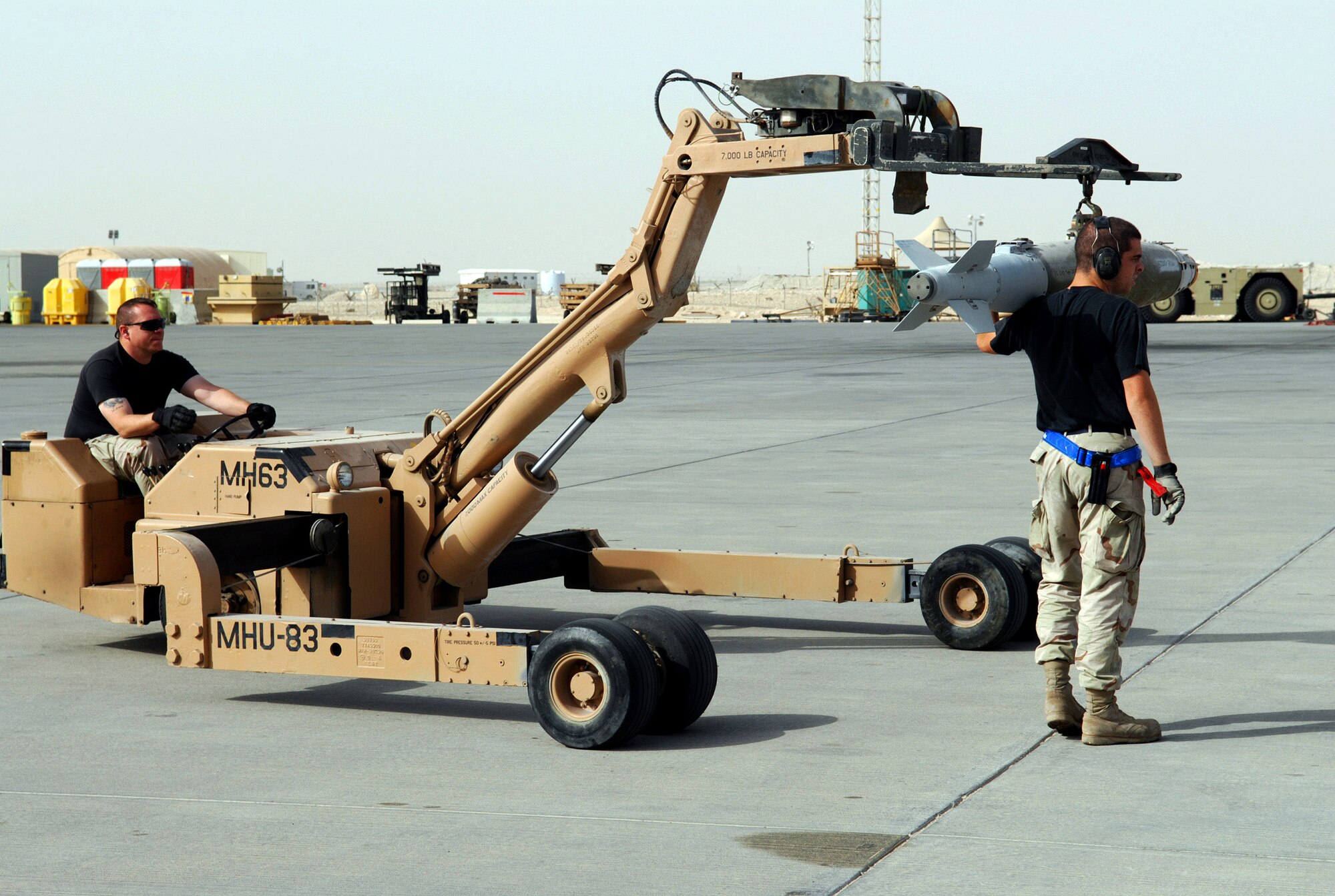 Senior Airman Brett Williamson guides as Staff Sgt. Greg Eaton moves ordnance to be loaded on a B-1B Lancer Jan. 10 at an air base in Southwest Asia. Both Airmen are assigned to the 379th Expeditionary Aircraft Maintenance Squadron. (U. S. Air Force photo/Staff Sgt. Douglas Olsen)