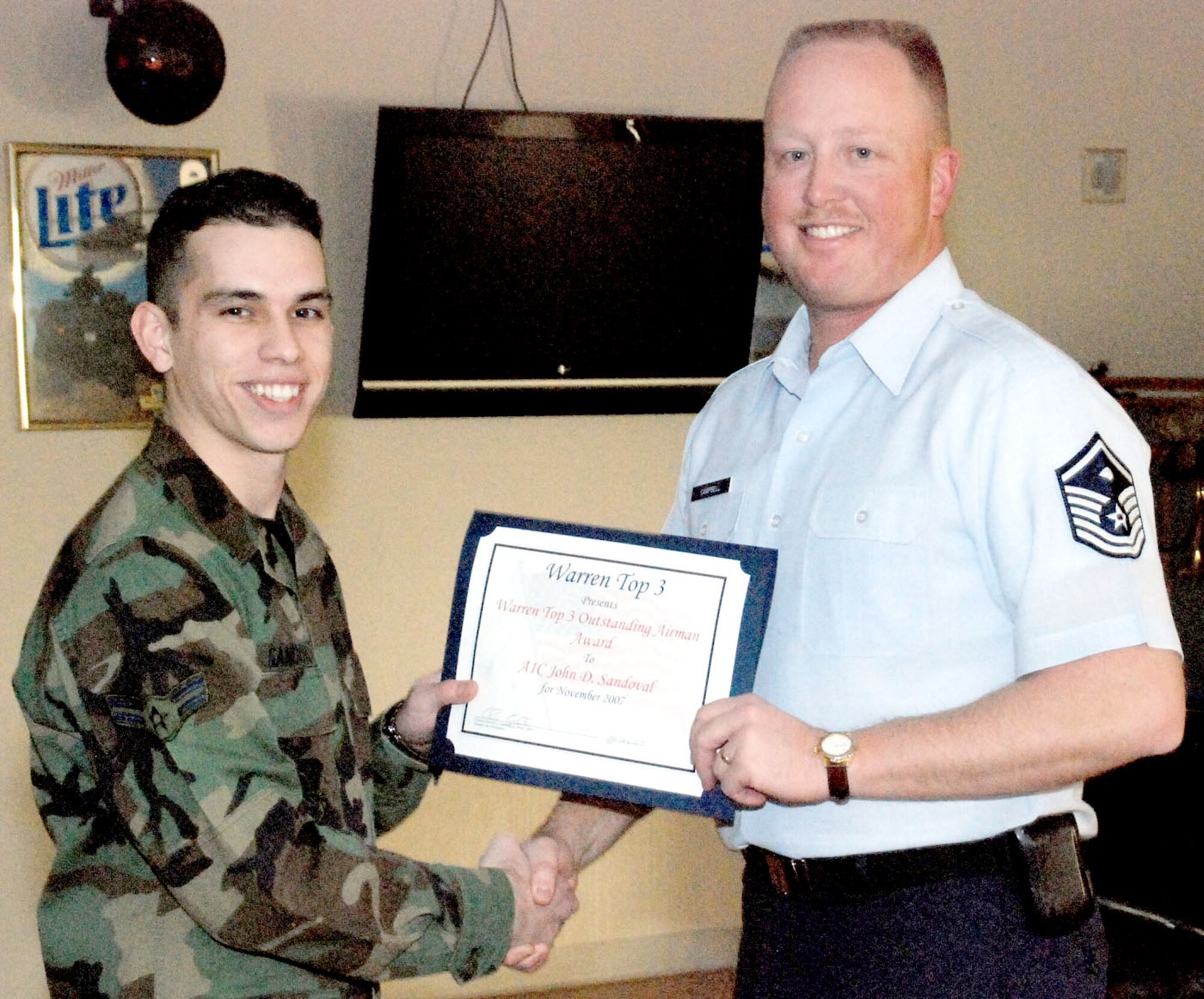Airman 1st Class John Sandoval, 90th Medical Operations Squadron, accepts the Top 3’s Outstanding Airman Award from Master Sgt. Chris Campbell, 90th Missile Maintenance Squadron first sergeant, during a ceremony in the Trail’s End Club Dec. 28. Airman Sandoval is the first Airman to receive recognition through the new award program.  Sergeant Campbell is the former president of the Top 3 organization (U.S. Air Force photo/Tech. Sgt. Dale Yates).