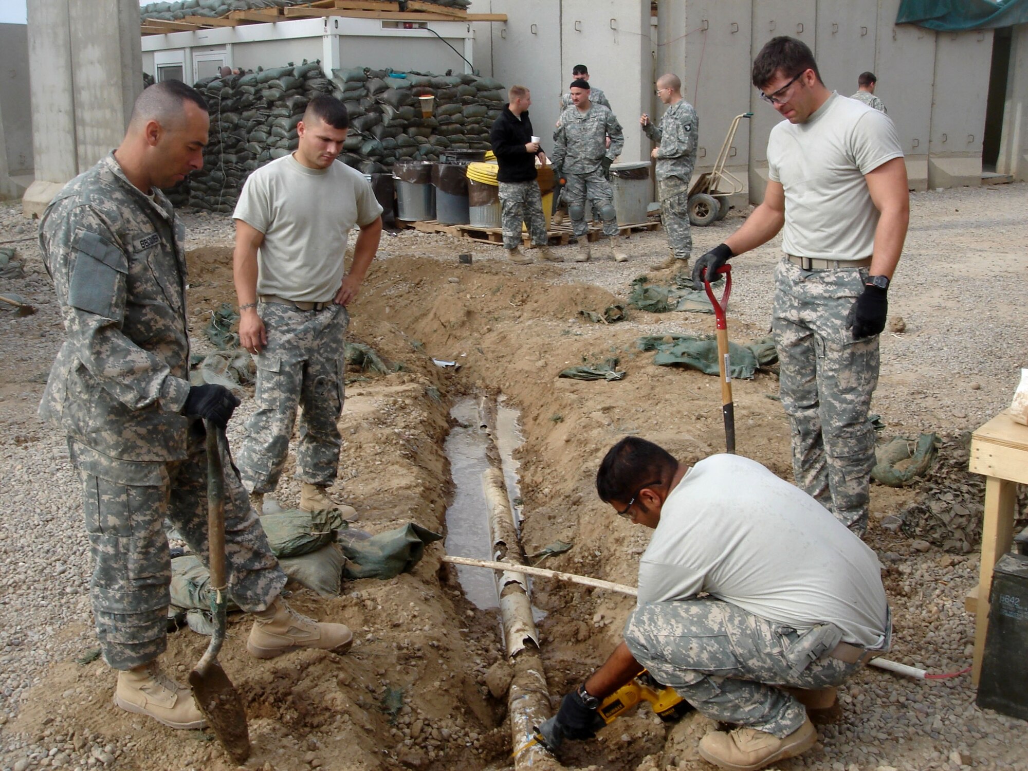 Tech. Sgt. John Becquer, (from left) Airman 1st Class Matthew Giacona and Staff Sgt. Caleb Dennis watch as Staff Sgt. Pranay Singh cuts through a drain pipe Jan. 11 at Patrol Base Olson, Iraq. The pipe will carry water to the showers, clothes washers and kitchen at Patrol Base Olson. The Airmen are all from the 732nd Expeditionary Civil Engineer Squadron Det. 6 deployed from Kadena Air Base, Japan. (U.S. Air Force photo) 
