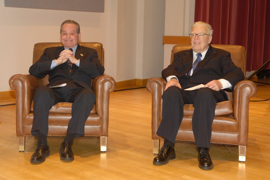 U.S. Air Force Band legends Col. Arnald D. Gabriel (left), conductor emeritus and former commander of The Band, and Chief Master Sgt. Floyd Werle, composer and arranger emeritus, enjoy the proceedings as two major rooms are dedicated in their names Jan. 9 at Hangar 2. (U.S. Air Force photo by Airman 1st Class Sean Adams.)