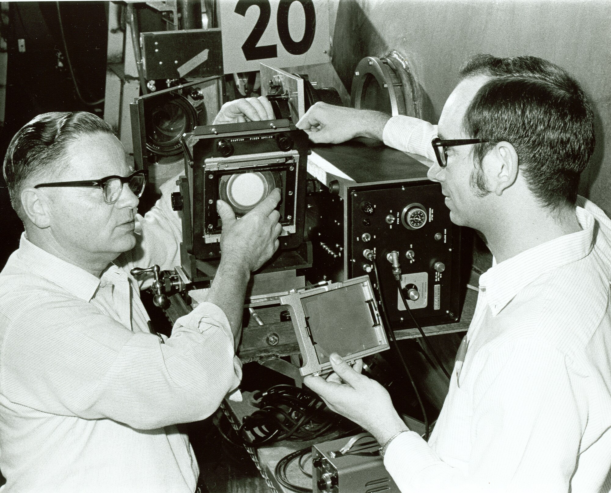 In 1972, AEDC engineers Otto Bock and Charley Enis discussed elements of a photopyrometer; a system in Arnold’s Hypervelocity Ballistic Range G. Bock developed the system with help from Enis.  A photopyrometer is used in conjunction with computer processing to provide test data required for reentry vehicle development. (AEDC photo)