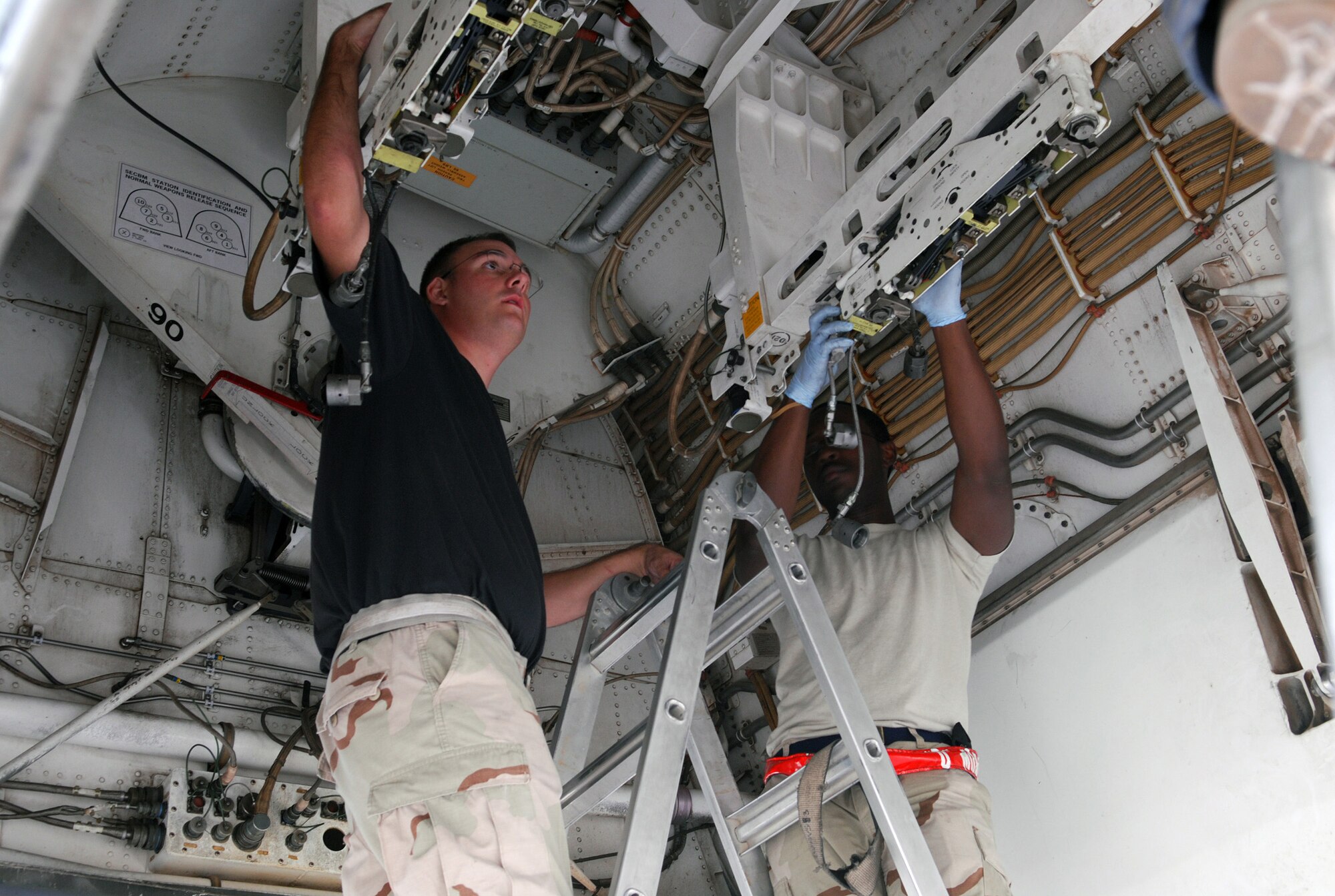 SOUTHWEST ASIA - Staff Sgt. Anthony Cords And Airman 1st Class Daniel Morton, 379th Expeditionary Aircraft Maintenance Squadron, clean the ordnance racks in the bomb bay of a B-1B Lancer Jan. 10 at a Southwest Asia air base. The bomber has just returned from a mission over Iraq. Both airmen are deployed from Dyess Air Force Base, Texas. (U. S. Air Force photo/Staff Sgt. Douglas Olsen)