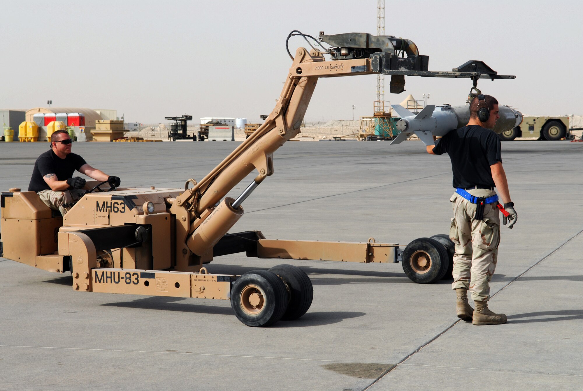 SOUTHWEST ASIA - Senior Airman  Brett Williamson, guides Staff Sgt. Greg Eaton as they move ordnance to load a B-1B Lancer Jan. 10 at a Southwest Asia air base.  Both airmen are assigned to the 379th Expeditionary Aircraft Maintenance Squadron. (U. S. Air Force photo/Staff Sgt. Douglas Olsen)