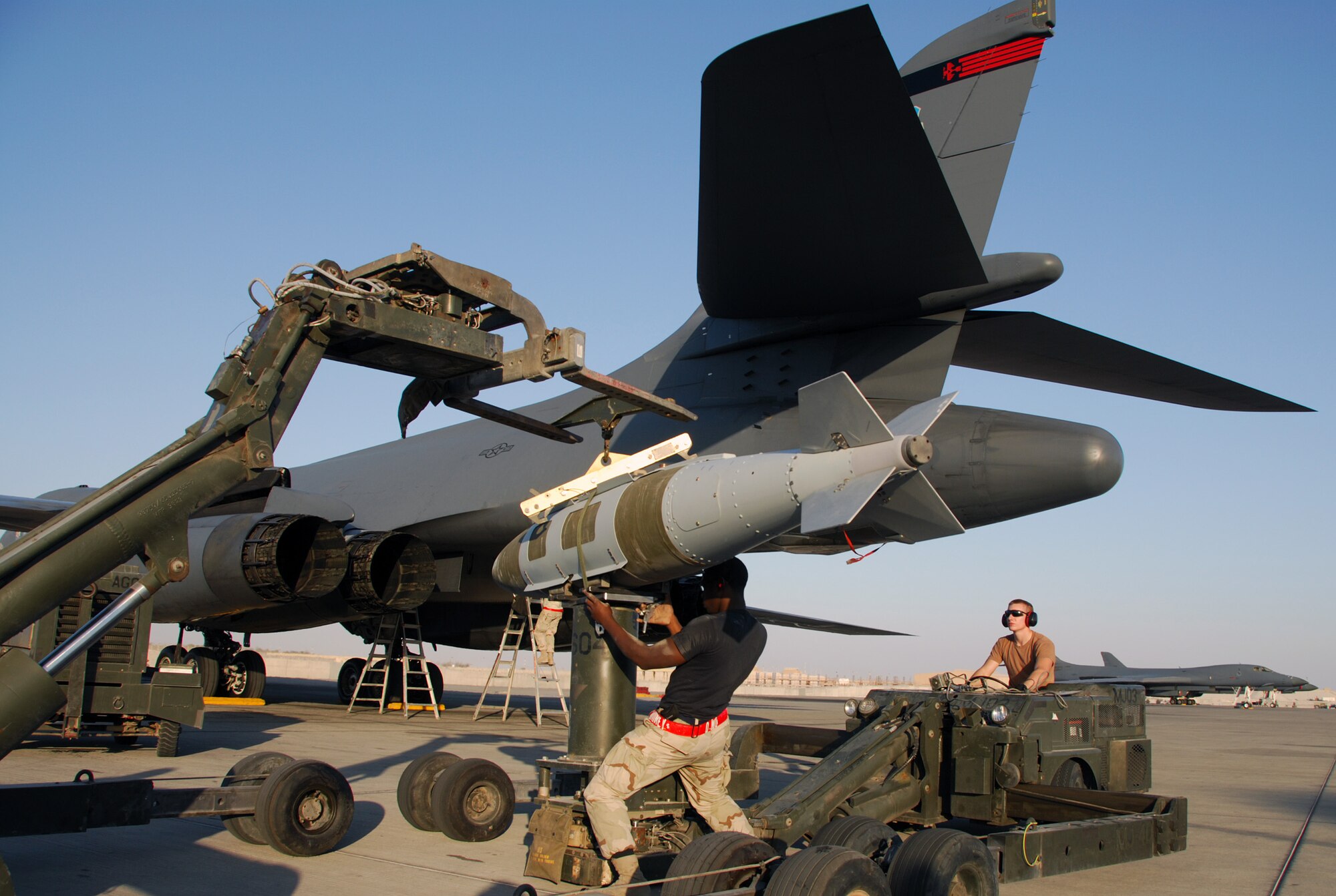 A weapons load crew with the 379th Expeditionary Aircraft Maintenance Squadron at a Southwest Asia air base, loads two 1,000 pound bombs onto a B-1B Lancer. Airman 1st Class Daniel Morton swings a bomb into position on the ram jammer operated by Airman David Pownell. The two Airmen are from Dyess. Airman Morton's home town is Anderson, S. C. AirmanPownell is from Appleton, Wisc. (United States Air Force photo by Staff Sergeant Douglas C. Olsen)