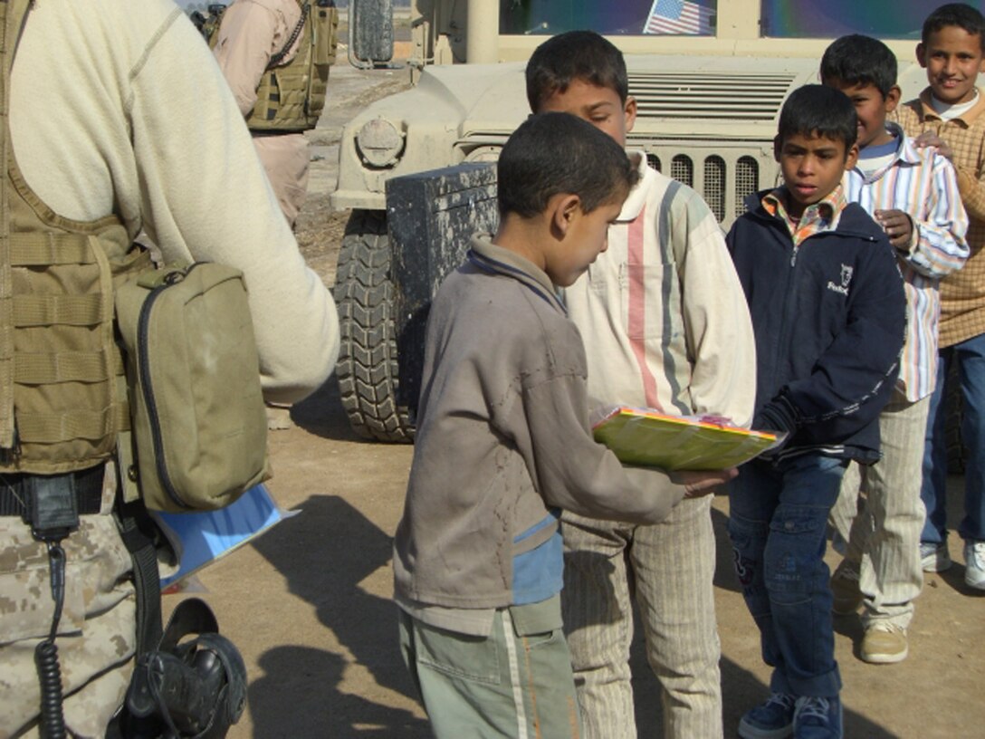 ALI AIR BASE, Iraq -- Iraqi children wait in line to receive school supplies from an Air Force Special Agent Dec. 29 in a village near An Nasiriyah. In just over a month, Airmen of the 407th Air Expeditionary Group collected thousands of school supply items, soccer balls, stuffed animals and toys from back home for the base's Operation Iraqi Child program. (Courtesy Photo)