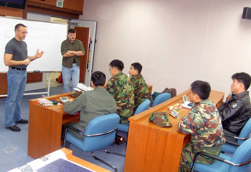 Tech. Sgt. Travis Bolt, (left), and Tech. Sgt. Troy Robey, (right), 607th Material Maintenance Squadron, Detachment 1, explain a common American phrase during an English class. Both Airmen have been voluntarily teaching English to Republic of Korea Air Force's 1st Fighter Wing personnel since September. (Photo by Ki Hyon Pak)