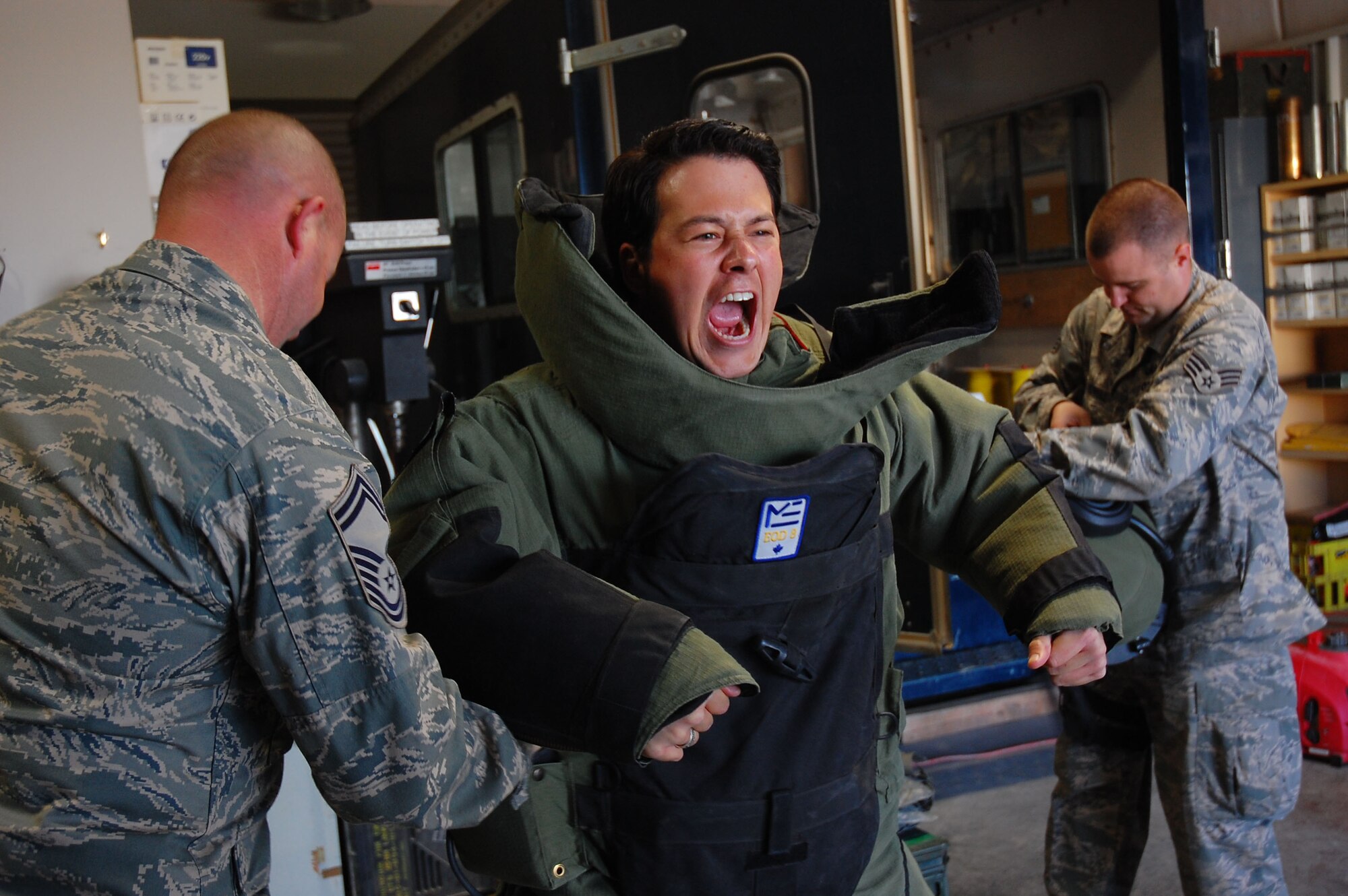SOUTHWEST ASIA -- Senior Master Sgt. Russell Corner and Senior Airman Charles Howell, assigned to the 386th Expeditionary Civil Engineer Squadron explosive ordnance disposal flight, suit-up Sean Mackin, vocals and violinist for the 'Yellowcard' band, during a tour of an air base in the Persian Gulf region Jan. 12, 2008. The tour was a way of saying thank you to the band for their five-day United Service Organizations' tour throughout the deployed theater. (U.S. Air Force photo/Senior Airman Patrick Dixon) (Released)