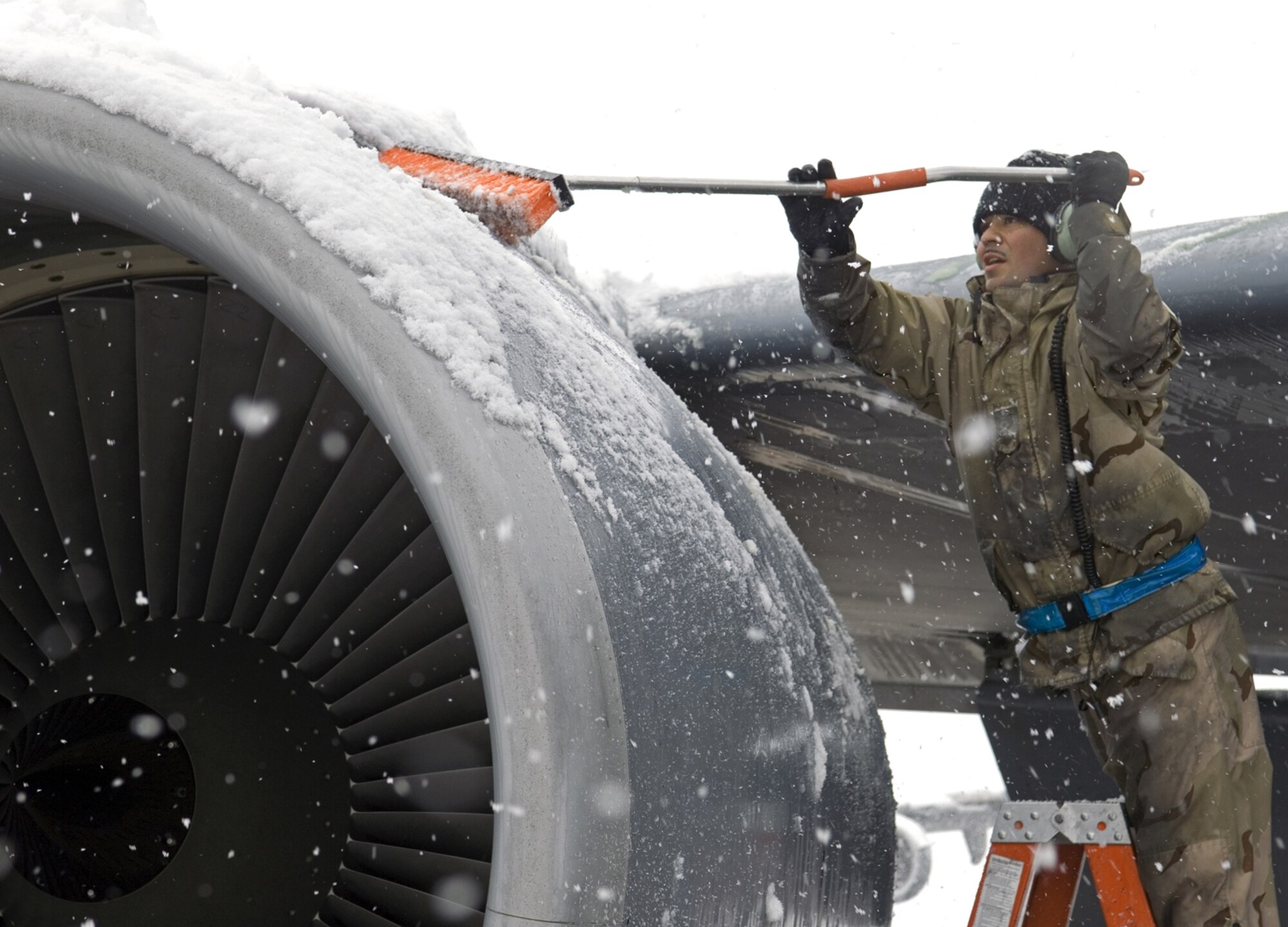 Staff Sgt. Manuel Garibay, 376th Air Expeditionary Maintenance Squadron crew chief, clears the snow off a KC-135 engine cowling. (U.S. Air Force photo by James Westfall)