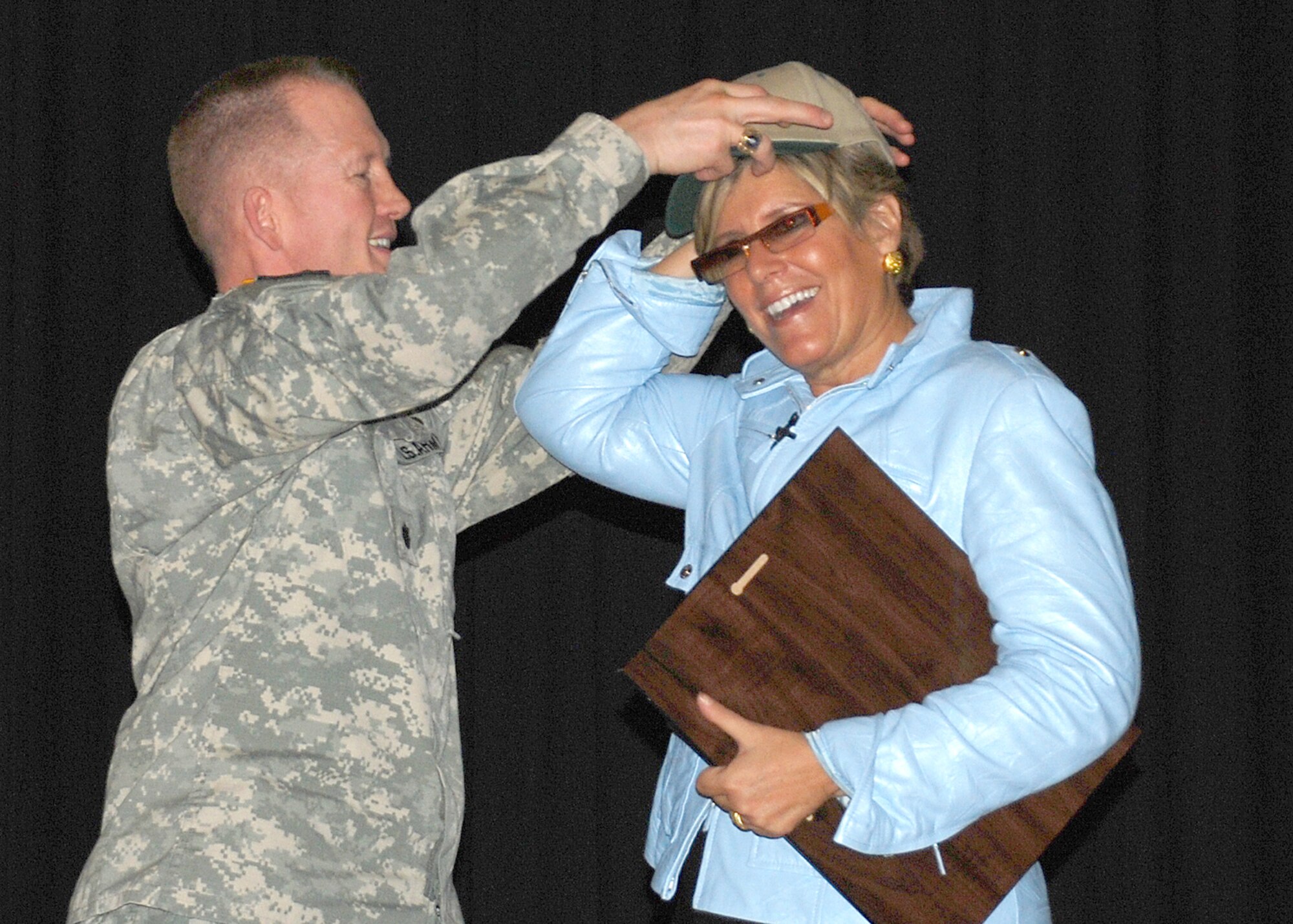 Army Lt. Col. Roger Cotton, Fort Dix deputy commander, presents Suze Orman with an award of appreciation Jan. 11 at the Timmerman Center on Fort Dix. Financial advisor Suze Orman spoke to servicemembers on how they can save money in day-to-day life and during deployments. (U.S. Air Force photo/Senior Airman Dilia DeGrego)
