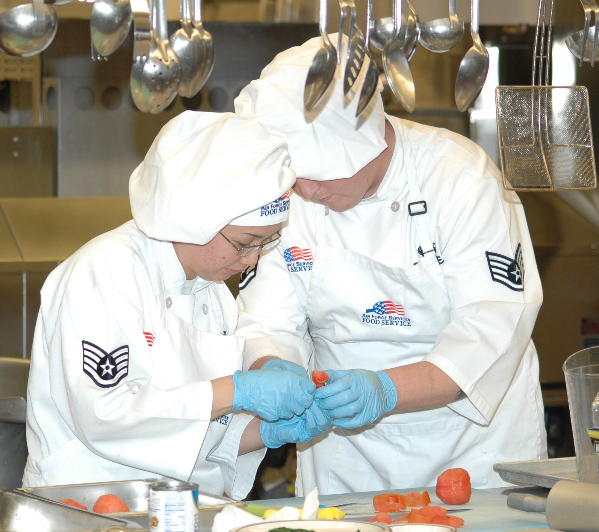 Staff Sgt. Cleofe Ugalde, 10th Missile Squadron senior missile chef, and Staff Sgt. Charles Savage, 10th MS senior missile chef, prepare tomato roses to garnish their garlic-rosemary chicken and brown rice dish during the quarterly Warrior Chef competition at the Elkhorn Dining Facility Jan. 10. The 490th MS team won the competition.(U.S. Air Force photo/Airman 1st Class Dillon White)