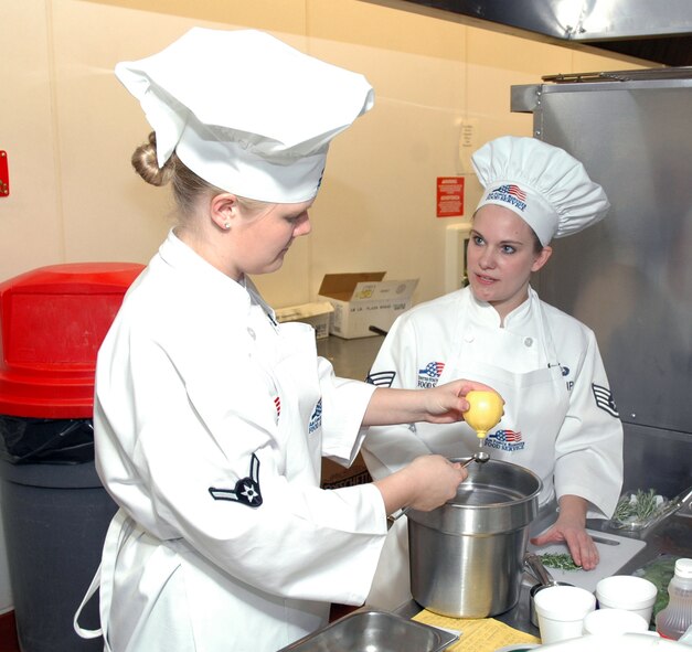 Airman Elizabeth Parker, 490th Missile Squadron missile chef, measures lemon juice and listens to Staff Sgt. Amy Phillips, 490th MS senior missile chef, discuss their recipe during a Warrior Chef competition at the Elkhorn Dining Facility Jan. 10. The team won first place in the competition with their baked halibut with rosemary cream sauce, wild rice and fresh spinach dish. (U.S. Air Force photo/Airman 1st Class Dillon White)