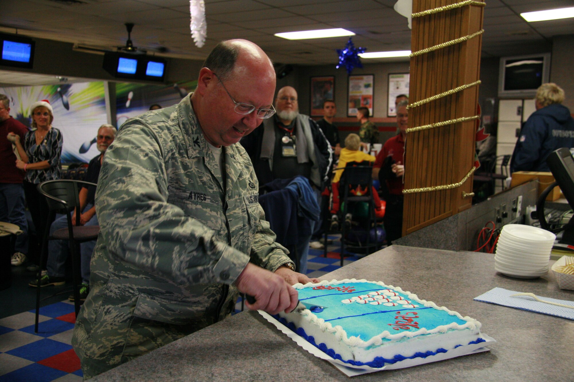 Cutting the cake to feed hungry bowlers at the Thede Bowling Center pin machine dedication ceremony is Col. Richard Ayres, 17th Training Wing commander. The bowling center officially opened its new pin machines Dec. 17. (U.S. Air Force photo by Julie Manuel)