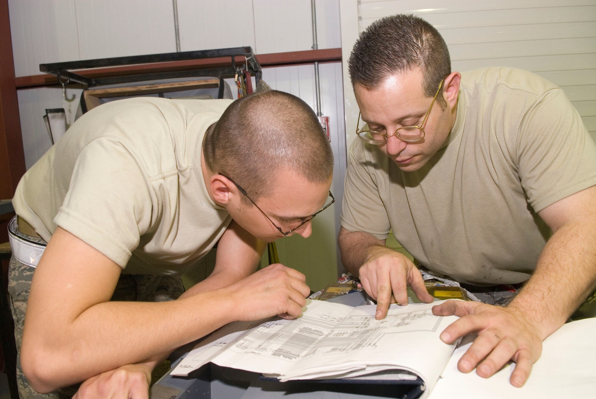 BALAD AIR BASE, Iraq -- Senior Airman Brandon Dutton and Tech. Sgt. Patrick Southard, both 332nd Expeditionary Maintenance Squadron weapons armament technicians, review the electrical layout of a bomb rack unit for the F-16 Fighting Falcon here, Jan. 14. The Airmen must be knowledgeable about wiring layouts to perform maintenance on the equipment. Airman Dutton is deployed from Luke Air Force Base, Ariz. and Sergeant Southard is deployed from Spangdahlem Air Base, Germany. (U.S. Air Force photo/Staff Sgt. Joshua Garcia)