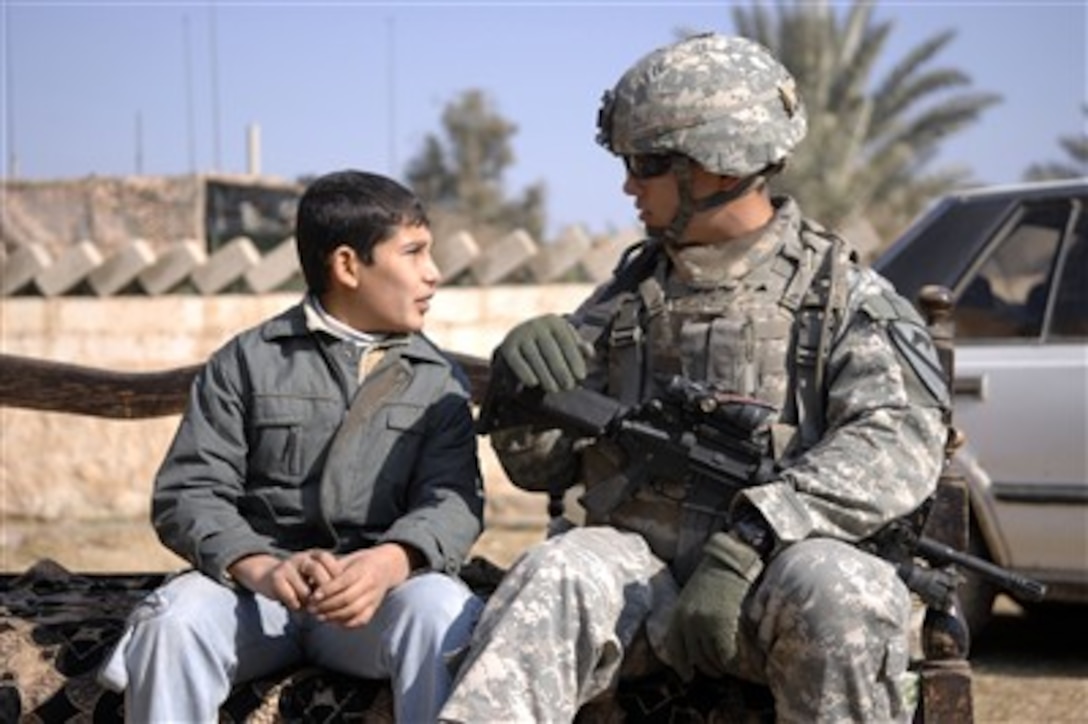 A U.S. Army soldier sits and talks with a young Iraqi boy in Hor al Bosh, Iraq, on Jan. 12, 2008.  The soldier is attached to the1st Brigade Combat Team, 1st Cavalry Division.  