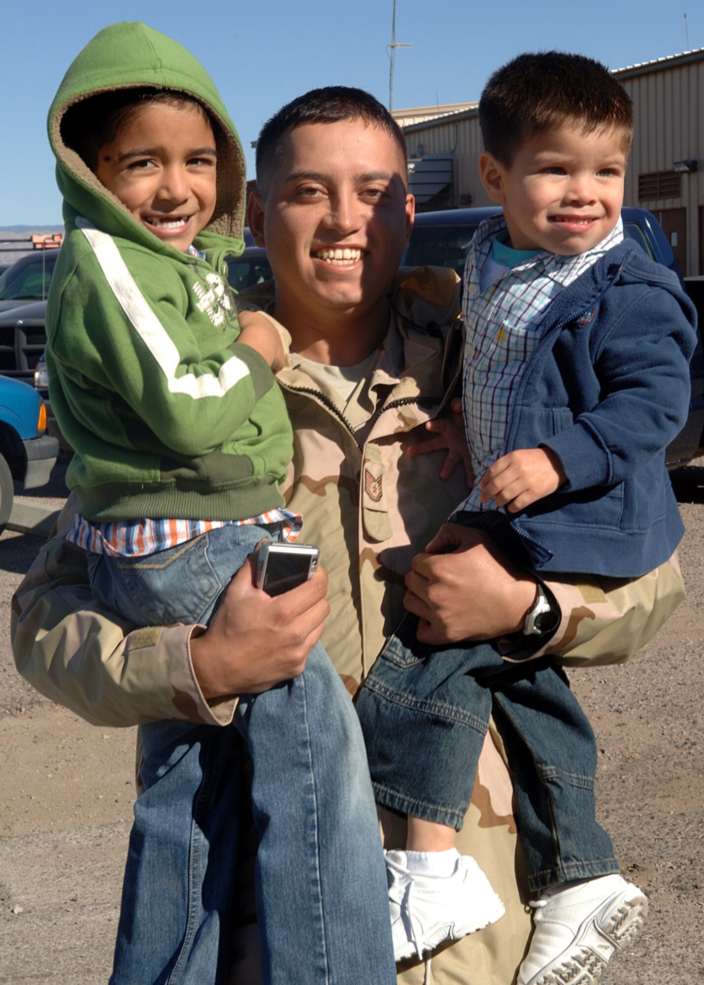 Staff Sgt. Michael De Los Santos, 49th Civil Engineer Squadron holds his two sons Gabriel and Donovan De Los Santos for the first time after a 4 month deployment to Al-Dhafra, Holloman Air Force Base, N.M Jan. 10, 2008. Sgt De Los Santos was one of the 45 Civil engineer members returning home from a four month deployment to Al-Dhafra. (U.S. Air Force photo/Airman 1st Class John D. Strong II) 