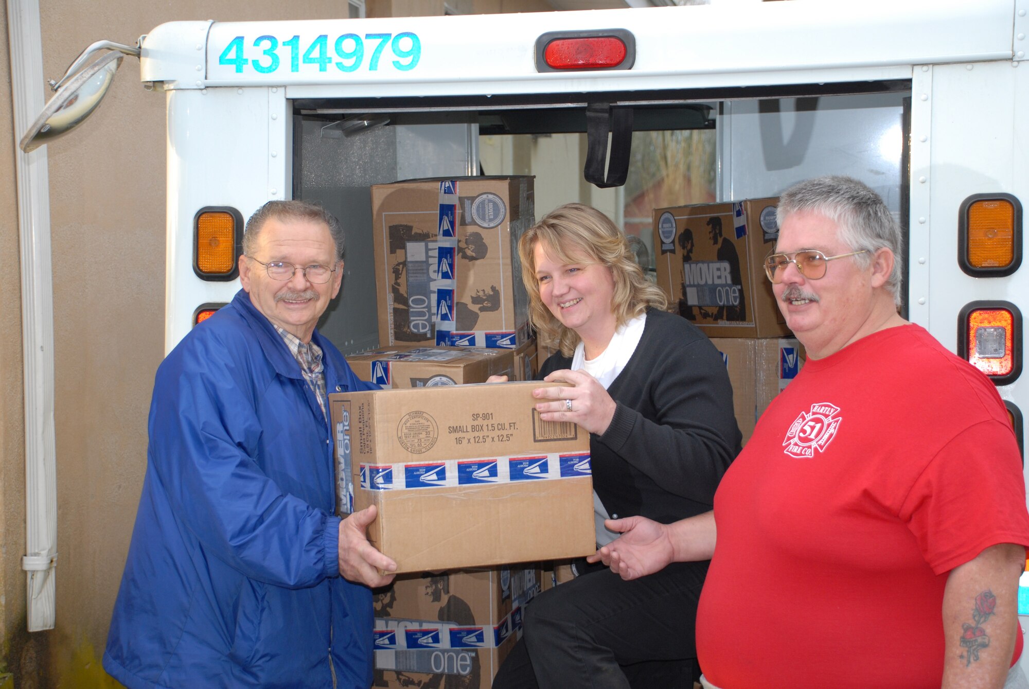From left, Frank Ballek Sr., vice president of the Hartly Volunteer Fire Co., hands a package to Hartly Postmaster Tammy Evans.  Also pictured is Tom Maguire, a member of the fire company.  The company collected more than 1,440 lbs. of donated goods from Central Delaware residents to be shipped to servicemembers serving in the U.S. Central Command area of responsibility. (U.S. Air Force photo/Master Sgt. Steve Marciniak)