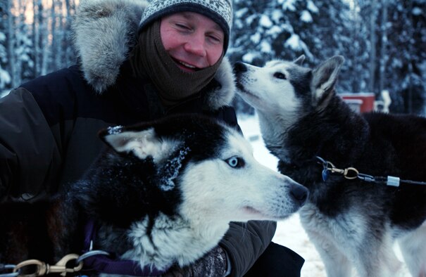 EIELSON AIR FORCE BASE, Alaska--Maj. Blake Matray, 168th Air Refueling Wing KC-135 pilot, enjoys a playful moment with his racing sled dogs Whit (left) and Boomer (right) before preparing them for practice.  Major Matray operates the Sled Dog Fund, Inc., a non-profit organization which uses dog sledding racing events to promote awareness and raise funds for disabled children. (U.S Air Force photo by Staff Sgt Eric T. Sheler)
