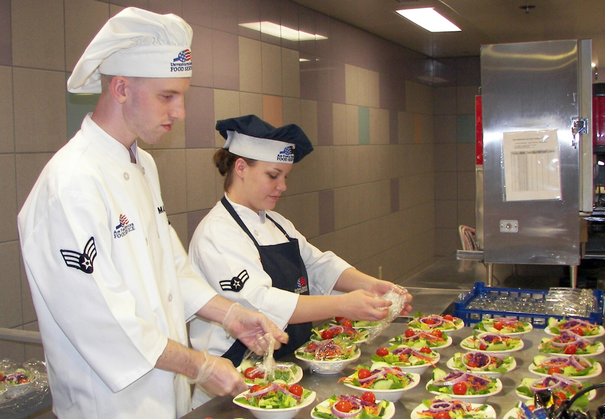 Senior Airman Tim Mattson and Airman First Class Jessica Baldwin, food services specialists, prepare salads for the quarterly birthday meal at the Ray V. Hensman Dining Facility. Following the salads, Airmen were served lobser, steak and shrimp along with dessert and prizes. (photo by Senior Airman Jessica King)