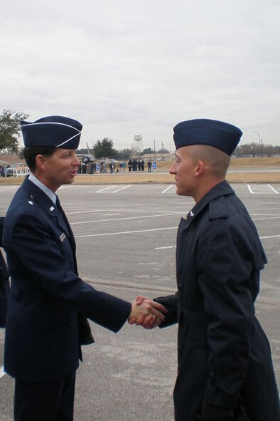 Airman 1st Class Kyle Causey (right), former Hanscom Life Guard, receives a coin at Air Force Basic Training Graduation Jan. 5 from Brig. Gen. Darrell Jones, commander of the 37th Training Wing, Lackland Air Force Base, Texas, and former 66th Air Base Wing commander. Airman Causey was selected as Honor Graduate and is now attending training at Keesler Air Force Base, Miss. Airman Causey was granted a waiver from the Air Force Surgeon General to enter active duty after he had a cancerous tumor removed from his abdomen while in high school that disqualified him from military service. (Courtesy Photo.)